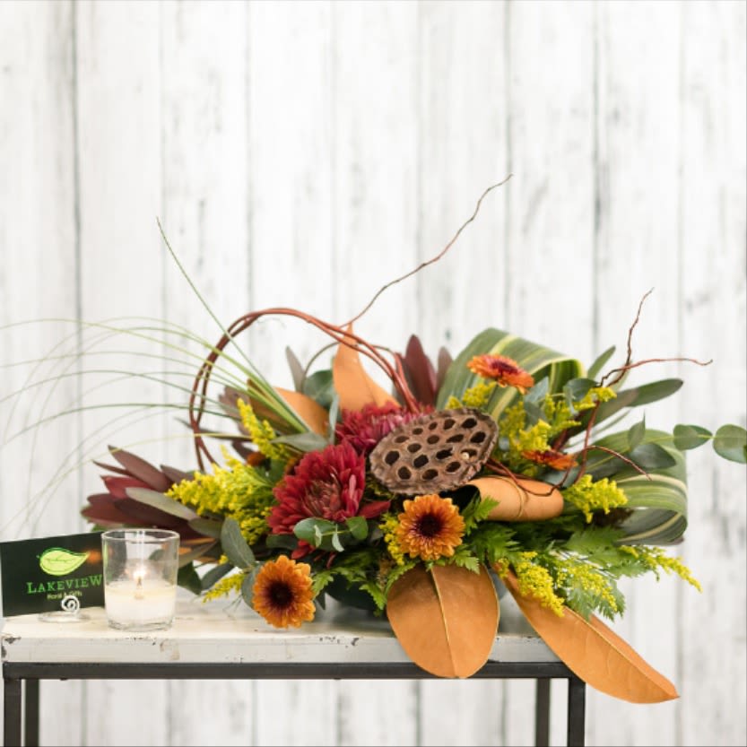 Low floral arrangement with orange and red blooms in a decorative container