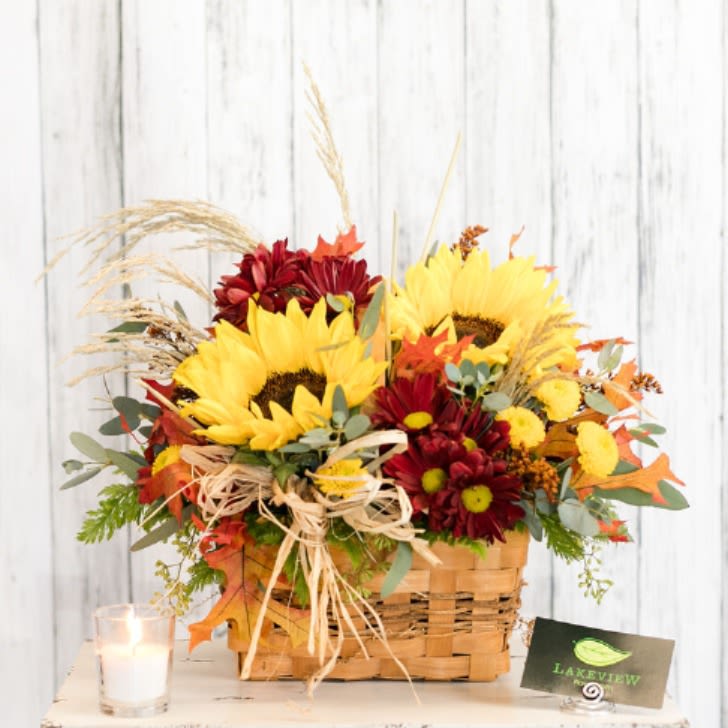 Basket arrangement of sunflowers and red mums with autumn accents