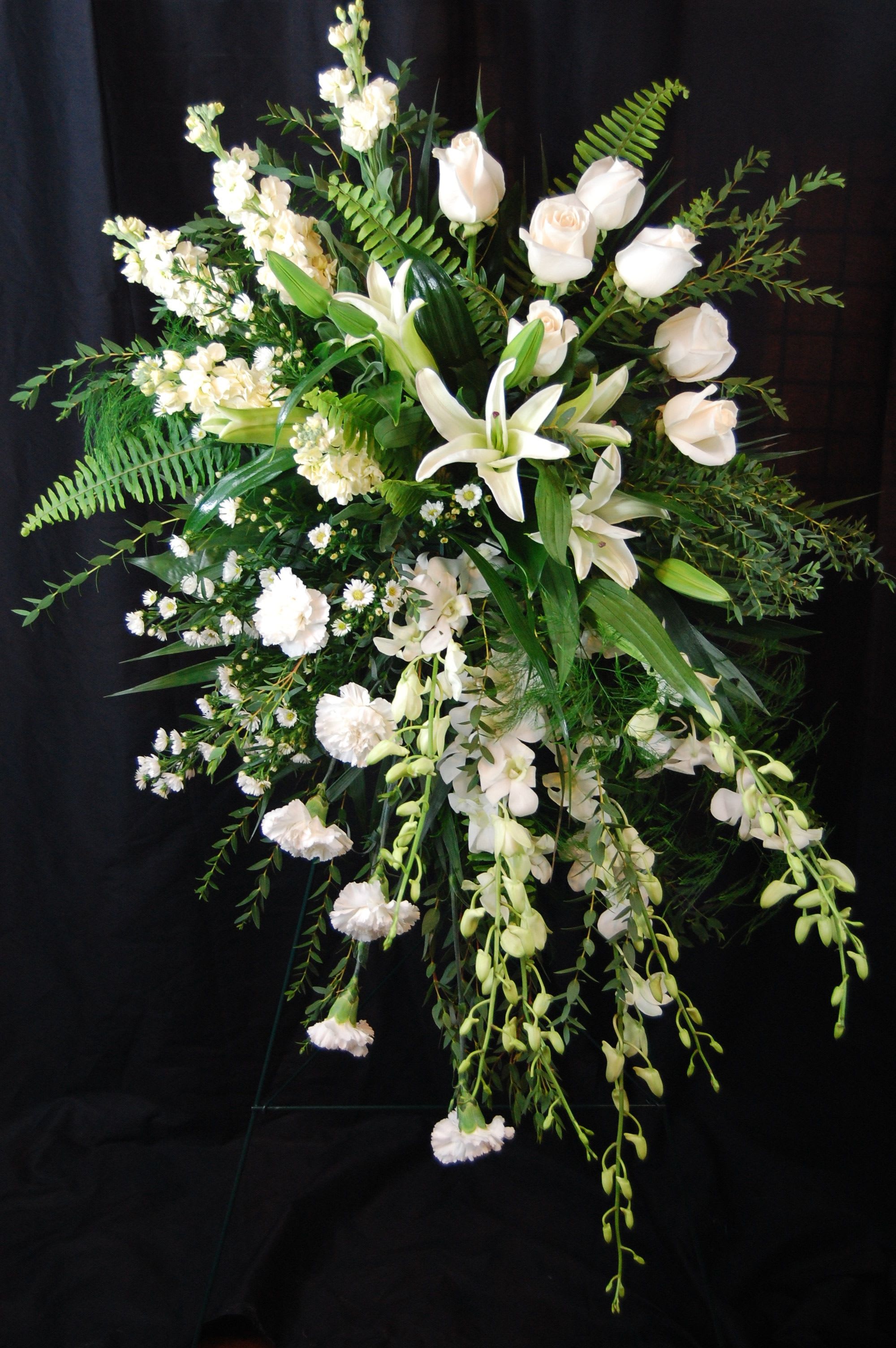 Rays Of Life - This beautiful spray will light up any room it's in. All the different beautiful white flowers and unique design will be remembered by all. 