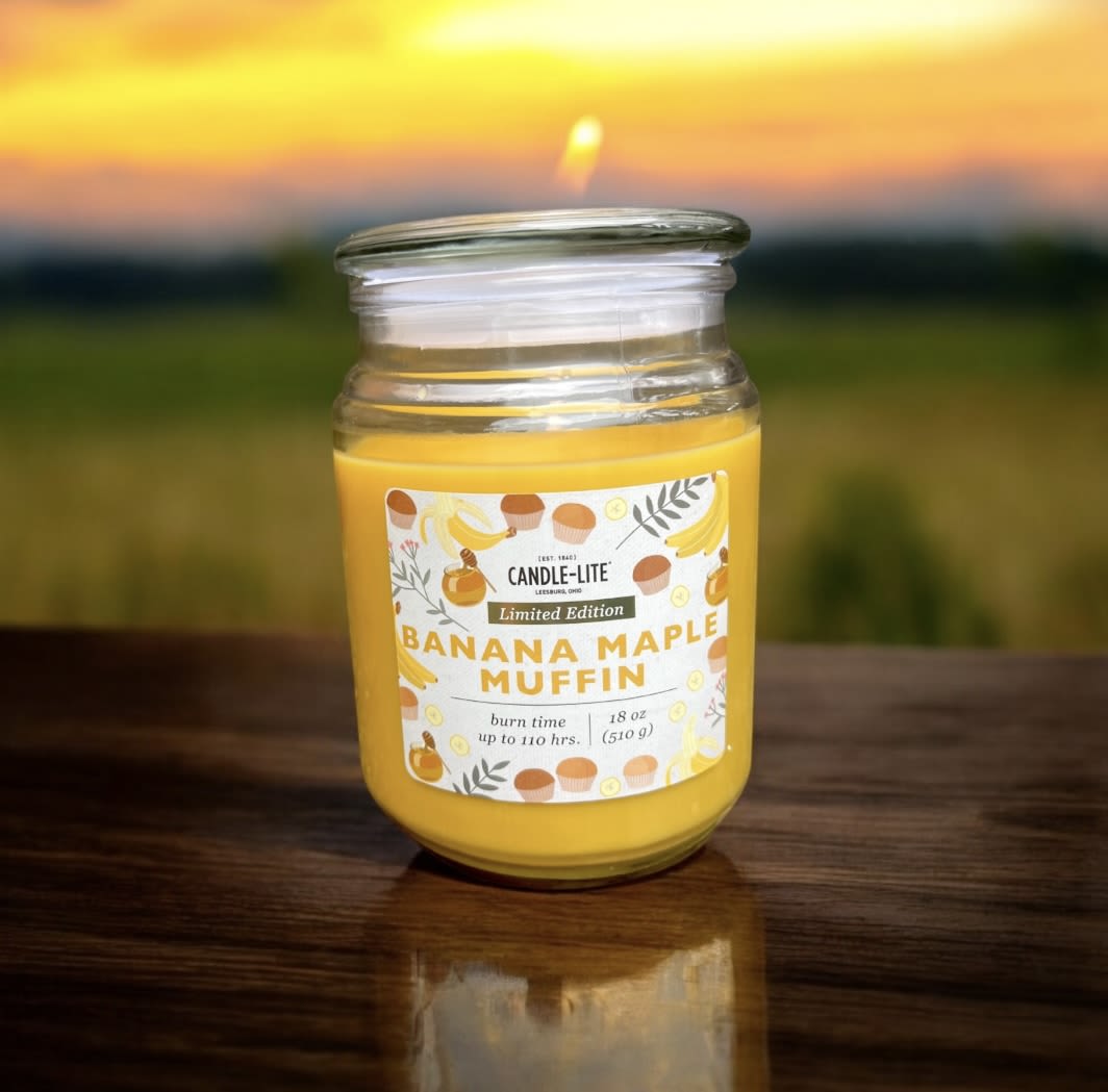 Yellow candle in a glass jar with a banana maple muffin label