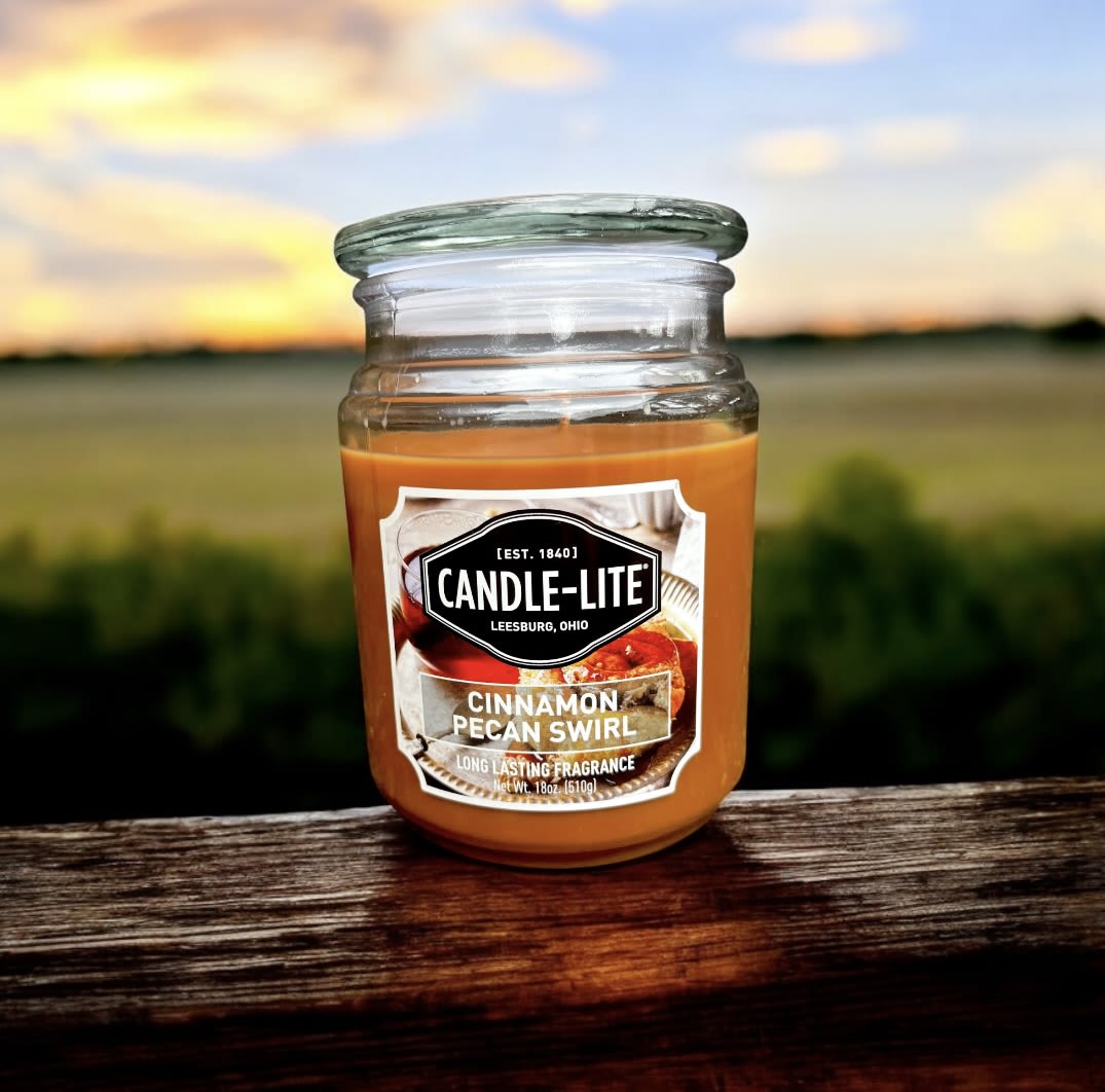 Jar candle labeled Cinnamon Pecan Swirl on a wooden surface