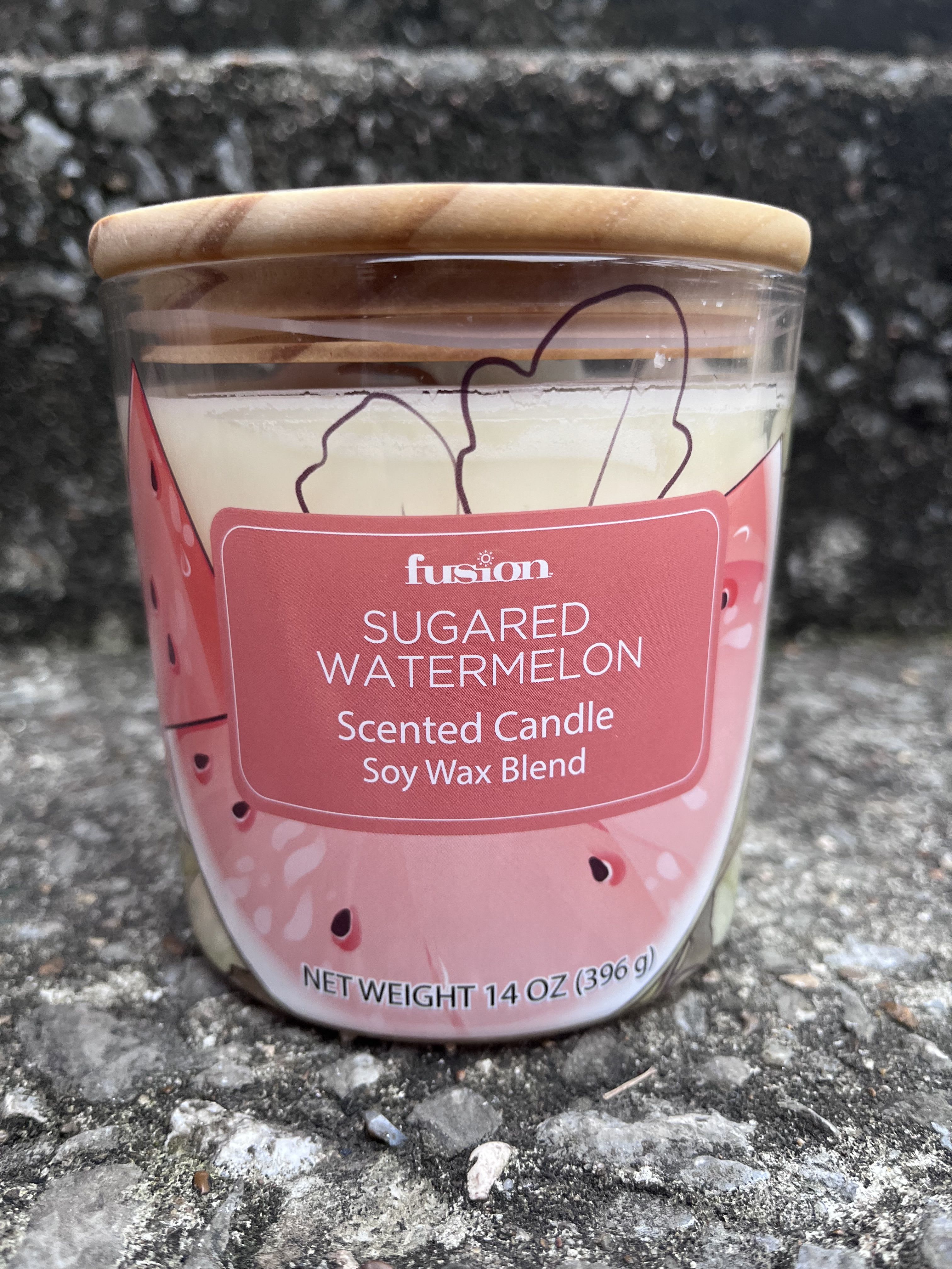 A sugared watermelon scented candle in a glass jar with a wooden lid