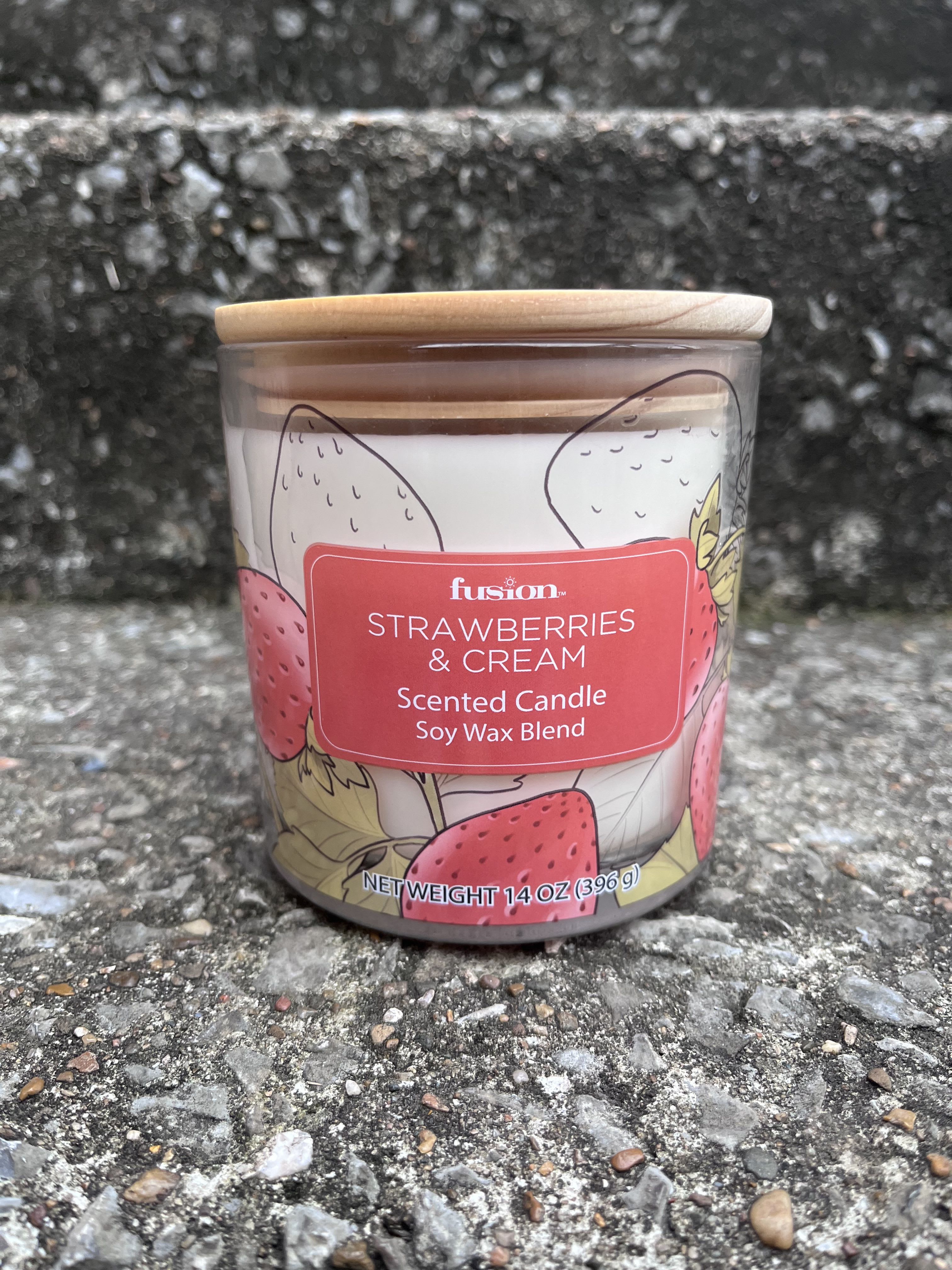 Strawberries and cream scented candle in a glass jar with a wooden lid