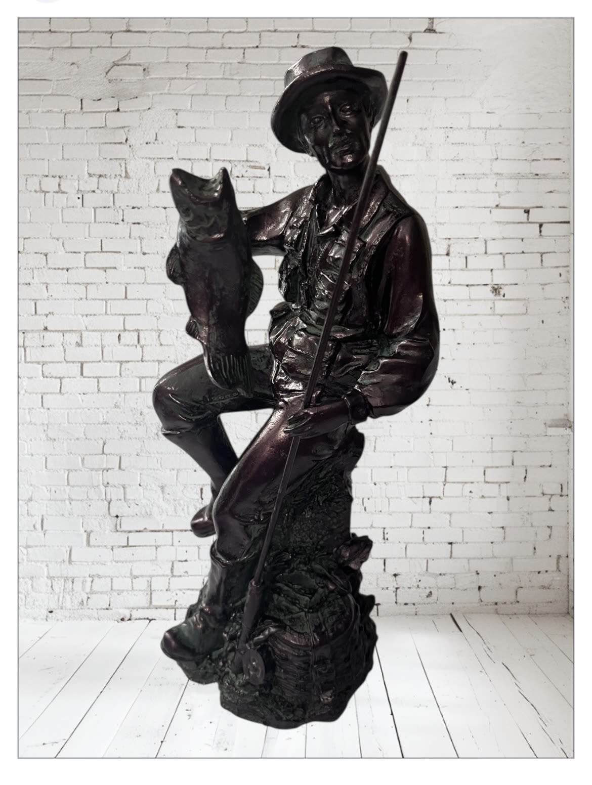 Bronze statue of a seated man holding a fish and a fishing pole