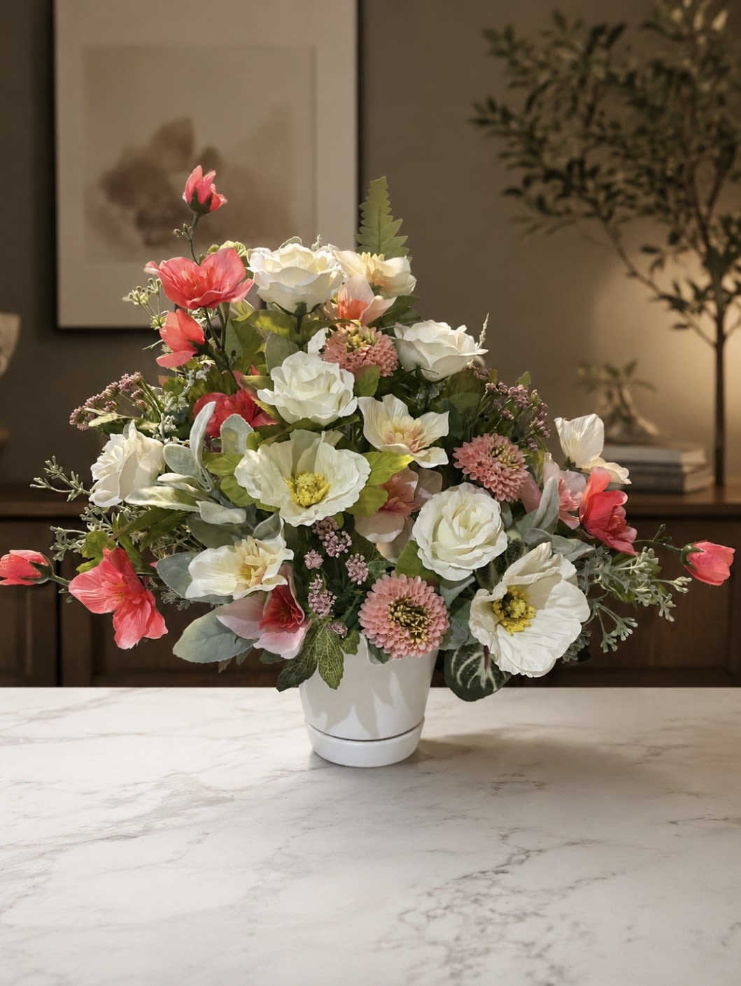 (Silk) Pastel Dream - A lush, garden-style bouquet of mixed white and pink blooms arranged one-sided in a white ceramic vase creates an immediate feeling of fresh romance-perfect as a birthday bouquet, a thank-you gift, or a cheerful spring centerpiece. The arrangement's soft coral-pink flowers and crisp white blossoms read as bright and uplifting; the person you're thinking of will feel genuinely celebrated by its light, airy presence.  This one-sided design features silk anemones, roses, daisies and other mixed florals layered densely with delicate branching accents and soft green foliage for texture. The rounded grouping sits neatly in a clean white ceramic vase, sized to showcase the full, compact silhouette while keeping surfaces tidy. The overall palette-white, pink and green-keeps the look versatile for many rooms and occasions.  Made for easy display, this arrangement is ready to place on a side table, mantle, or desk where the single-sided view faces the room. Silk flowers mean long-lasting color and no watering-an elegant, low-maintenance way to make someone feel truly seen.