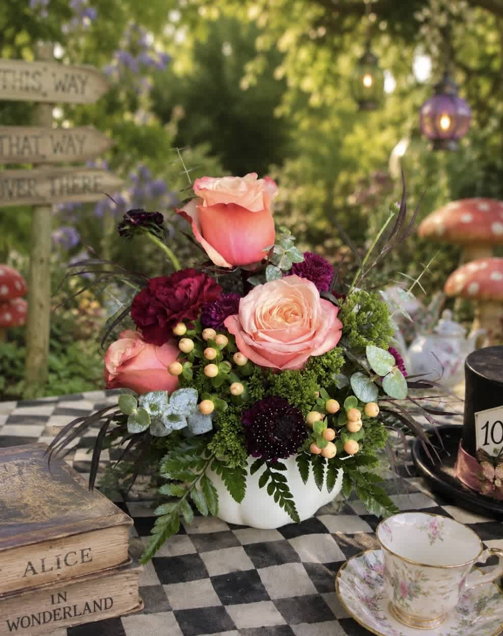 Pink and peach roses arranged in a white bowl with dark burgundy blooms