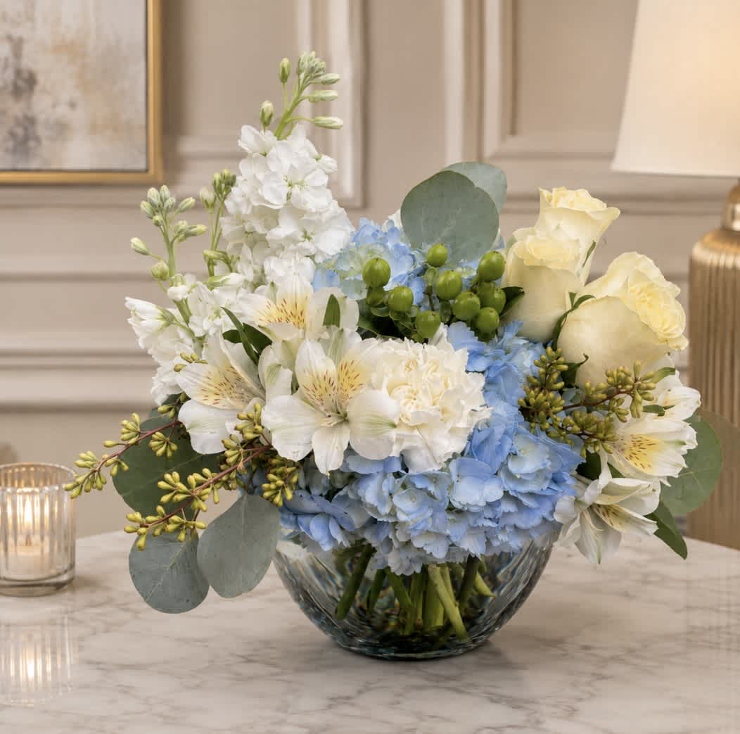 Blue and white flower arrangement in a glass bowl vase