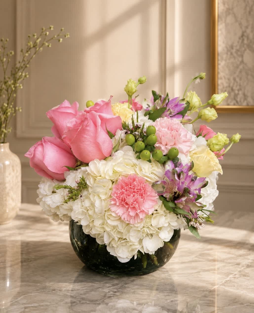 Pink roses and mixed blooms arranged in a dark glass vase
