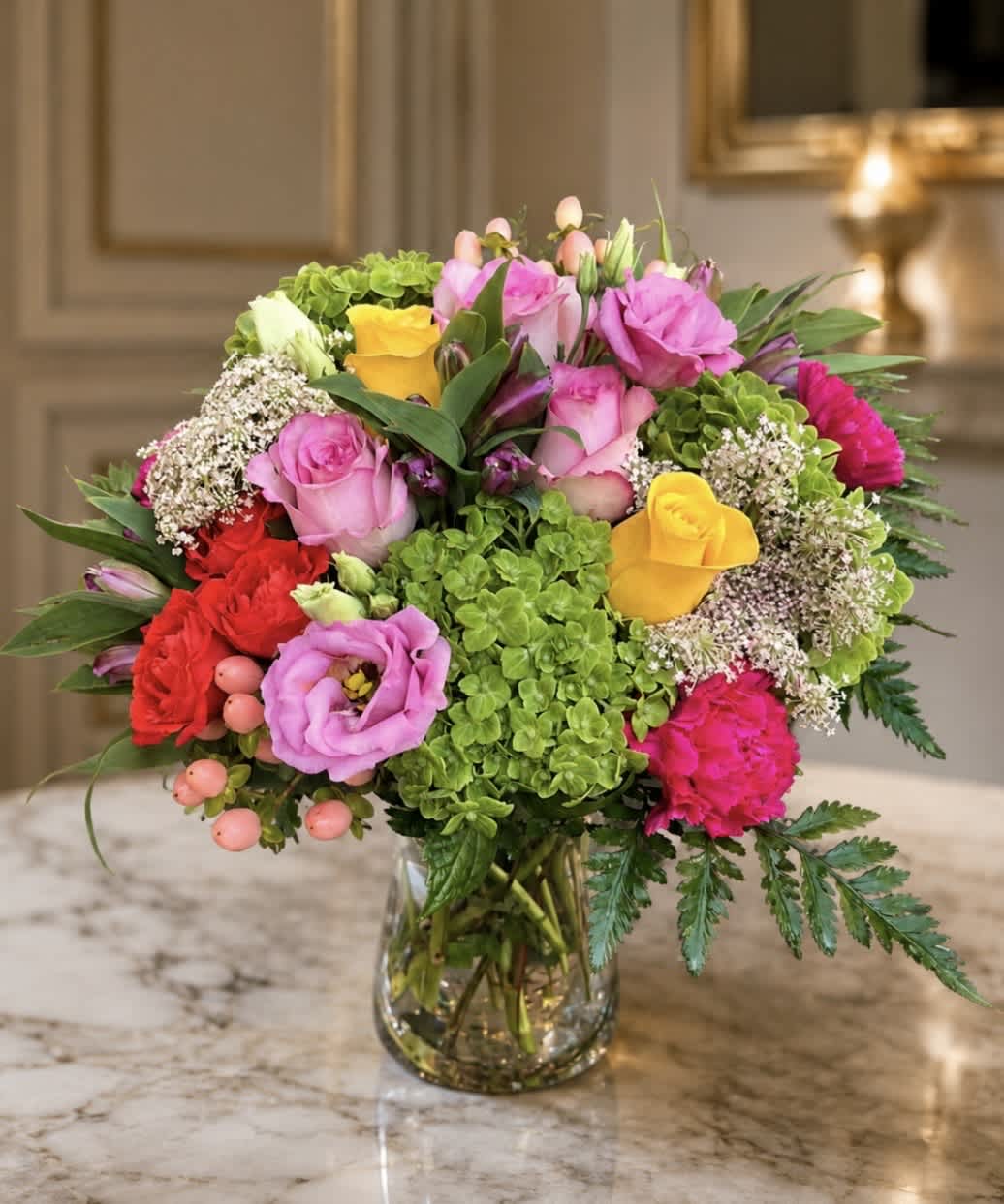 Mixed bouquet of pink, yellow, and red flowers in a glass vase