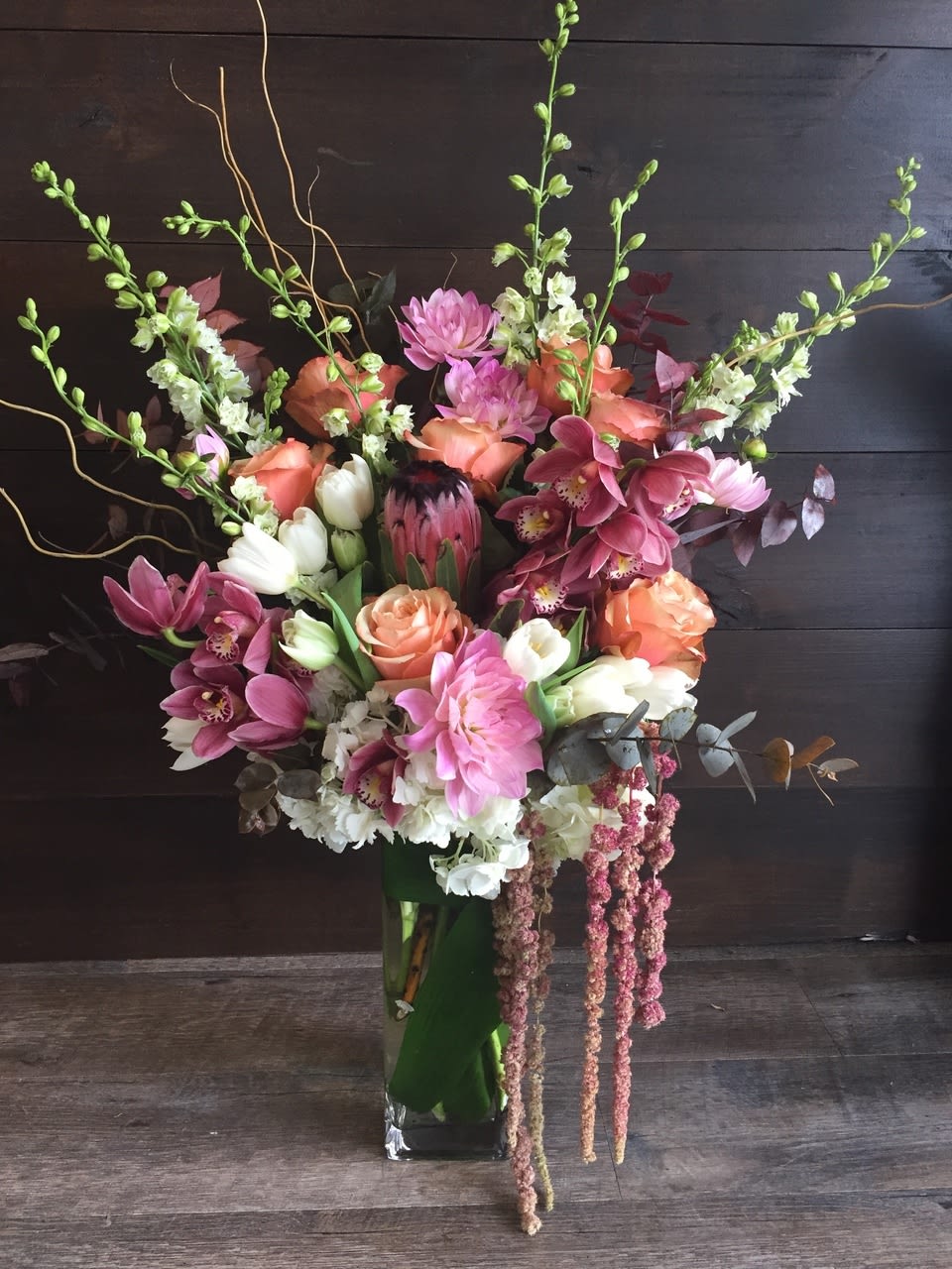Tall mixed bouquet with pink, peach, and white flowers in a glass vase