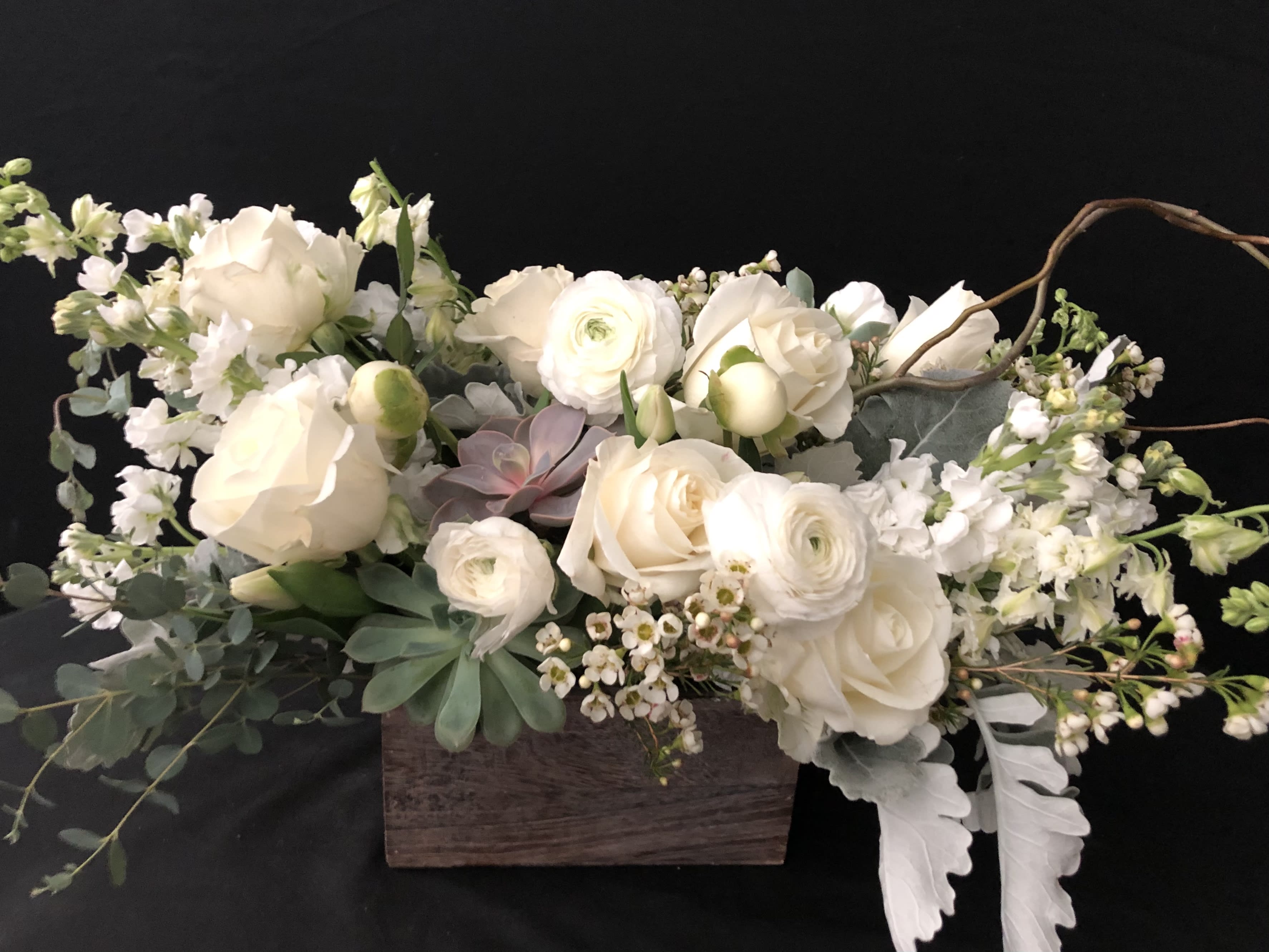 Cream floral arrangement in a wooden box with succulents and trailing greenery