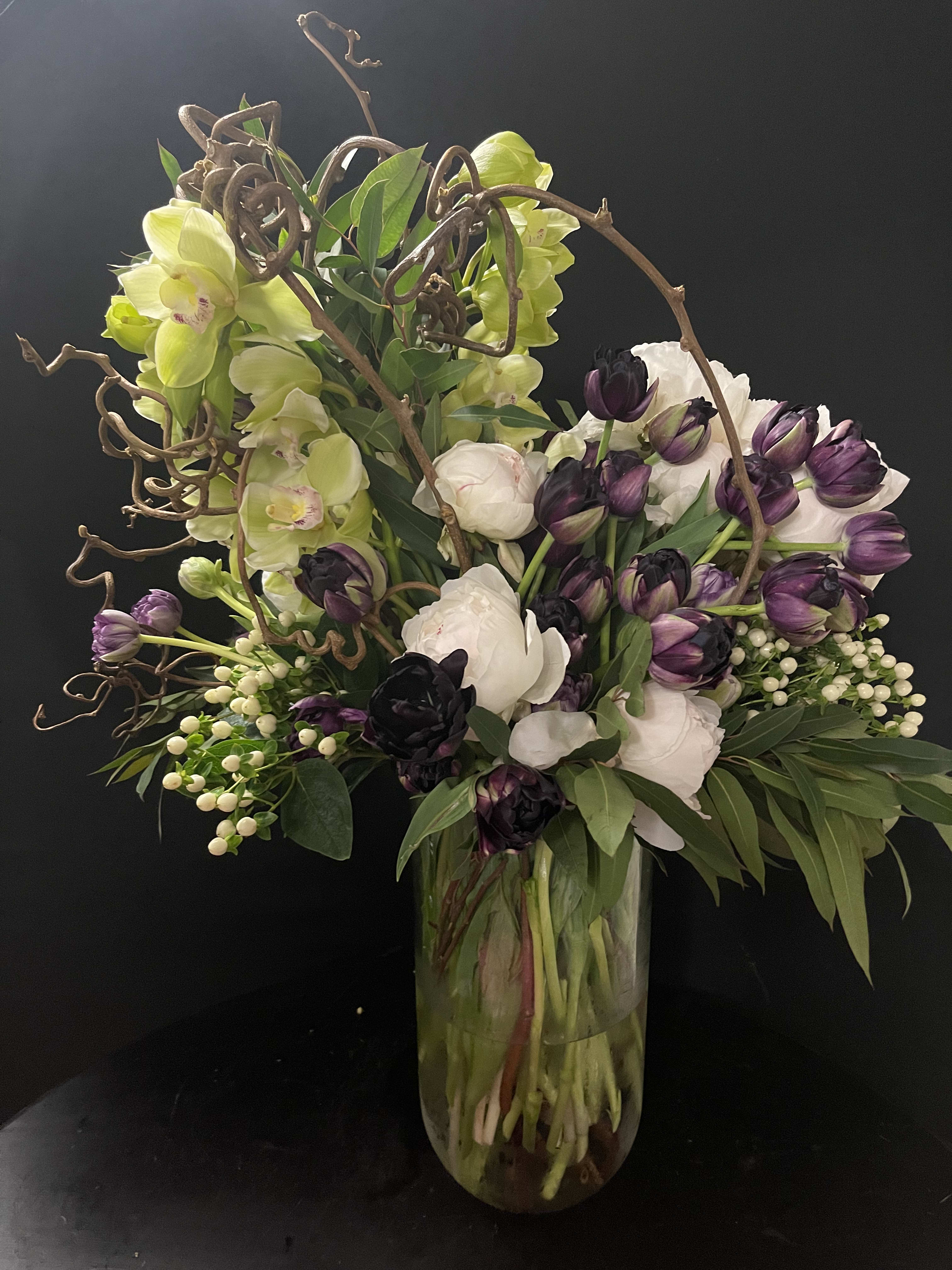 Bouquet of purple and white flowers in a glass vase with curly branches