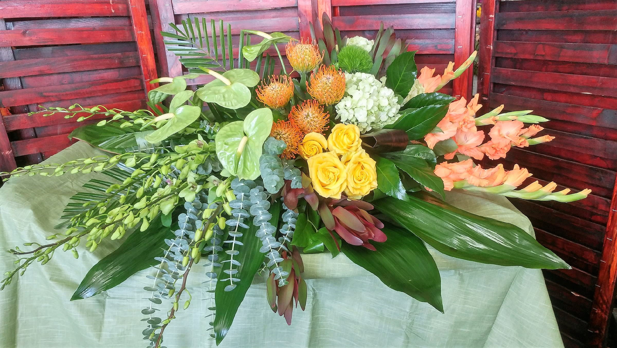 Tropical floral arrangement with yellow roses, orange blooms, and peach gladiolus