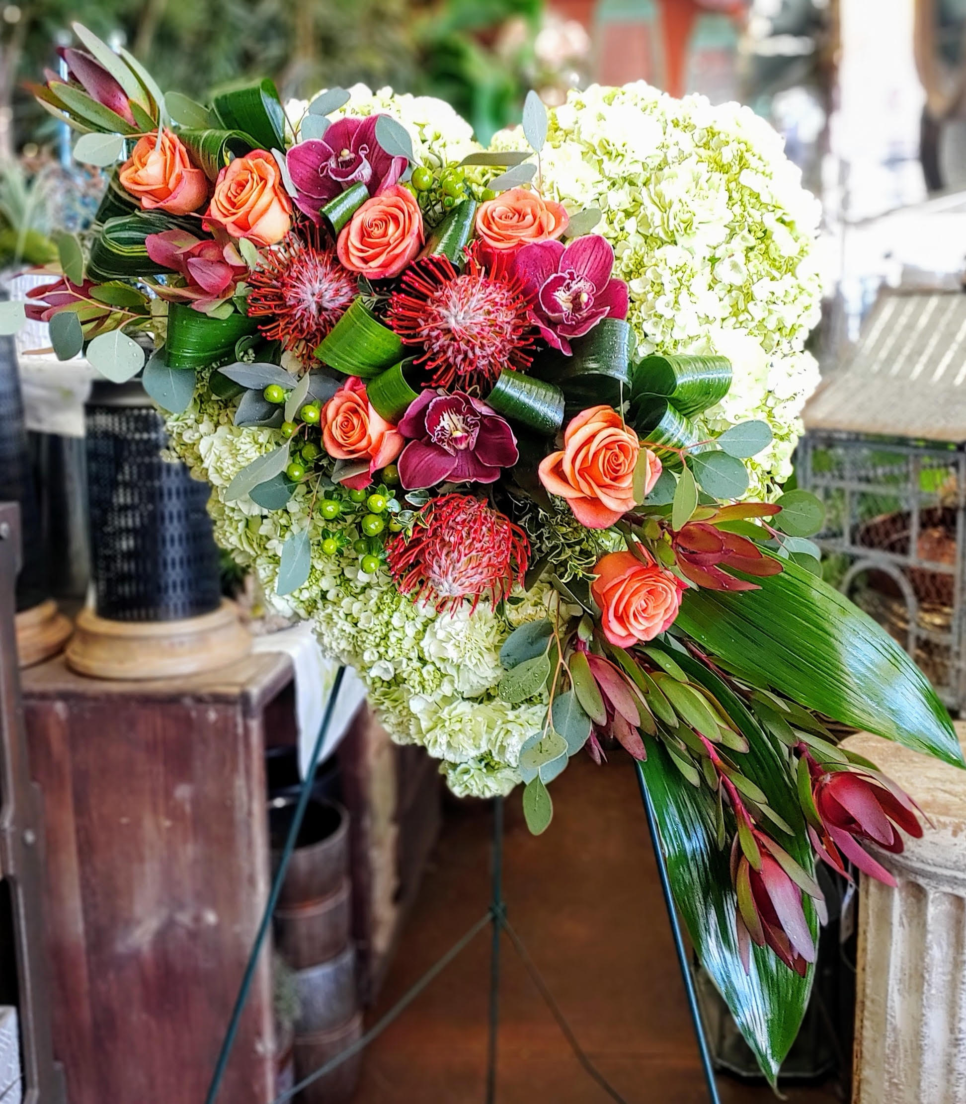 Heart-shaped floral arrangement with coral roses and white blooms