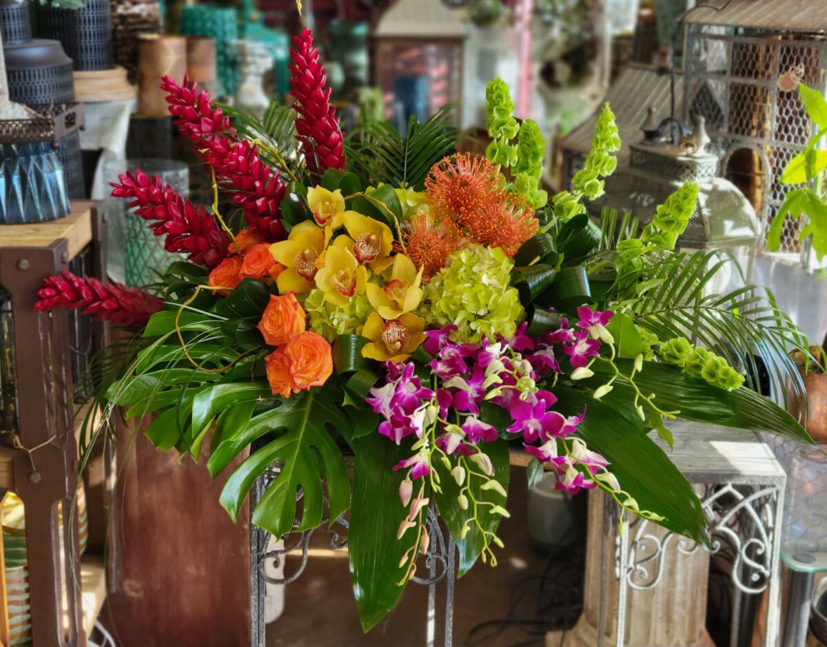 Tropical floral arrangement with orchids, orange roses, and red and green spikes