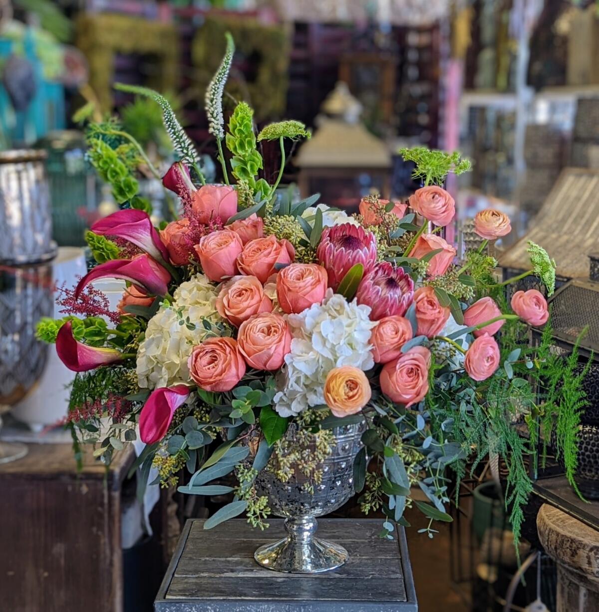 Pink and peach roses in a silver pedestal vase