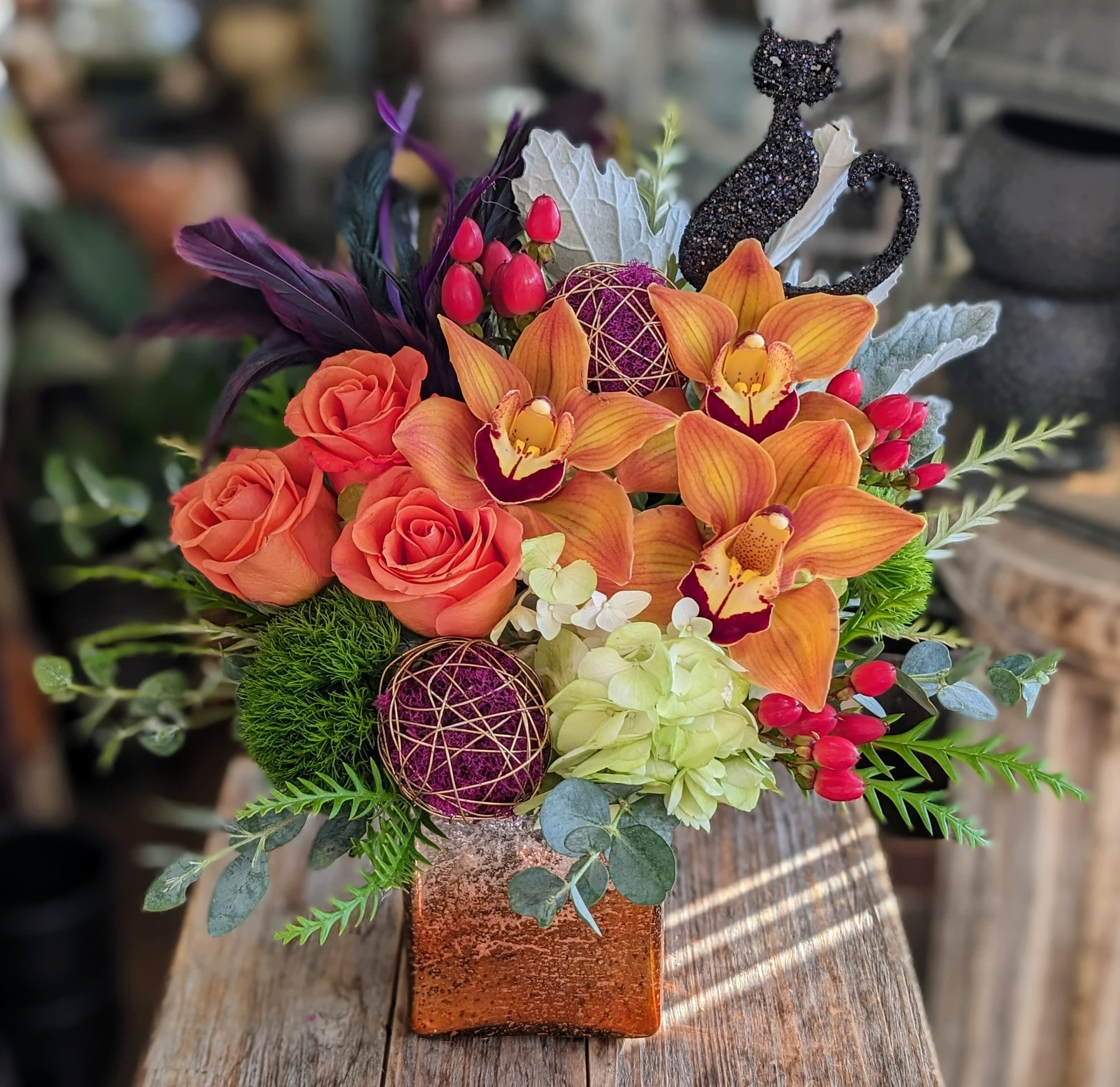 Enchanted -  Enchanted – A Bewitching Halloween Arrangement by Windmill Floral Expressions  Dare to be Enchanted this Halloween. Designed exclusively by Windmill Floral Expressions in Las Vegas, this spellbinding arrangement combines moody autumn blooms, dramatic textures, and a touch of shimmer — all crowned by a glittery black cat that brings a playful, magical energy to the design.  Rich seasonal hues mingle with preserved accents and artistic details, creating an arrangement that feels straight out of a midnight garden. Perfect for Halloween parties, spooky-chic home décor, or as a whimsical gift for someone who adores all things mysterious and beautiful.  Every piece is custom-crafted fresh to order, ensuring that no two Enchanted designs are ever the same. Created with artistry and care by your local family-owned Las Vegas florist, we offer same-day delivery to Henderson, Anthem, Ascaya, Inspirada, and MacDonald Ranch — just in time to cast a little floral magic.