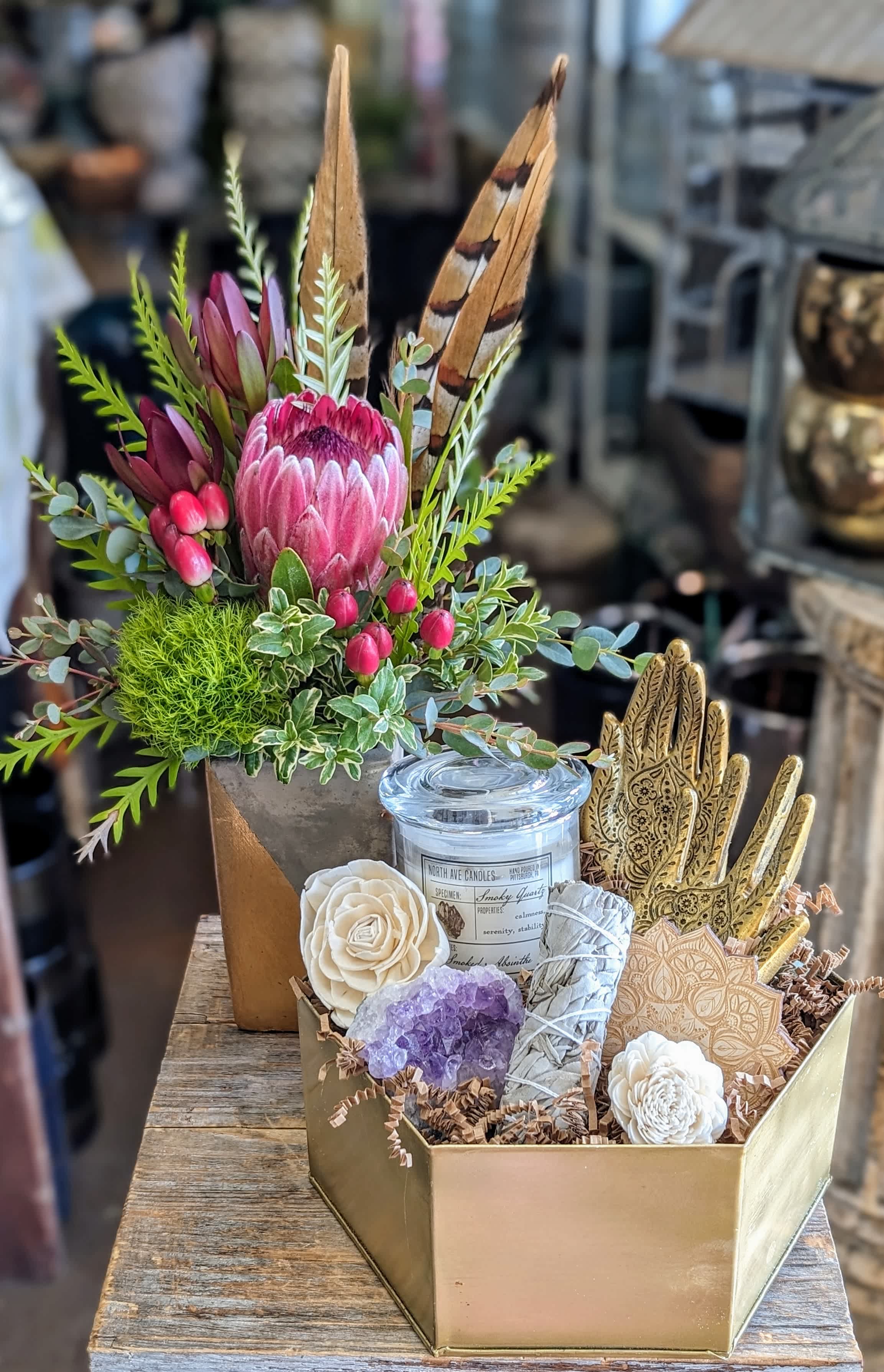 Gift box with a protea arrangement, candle, crystals, and decorative hands