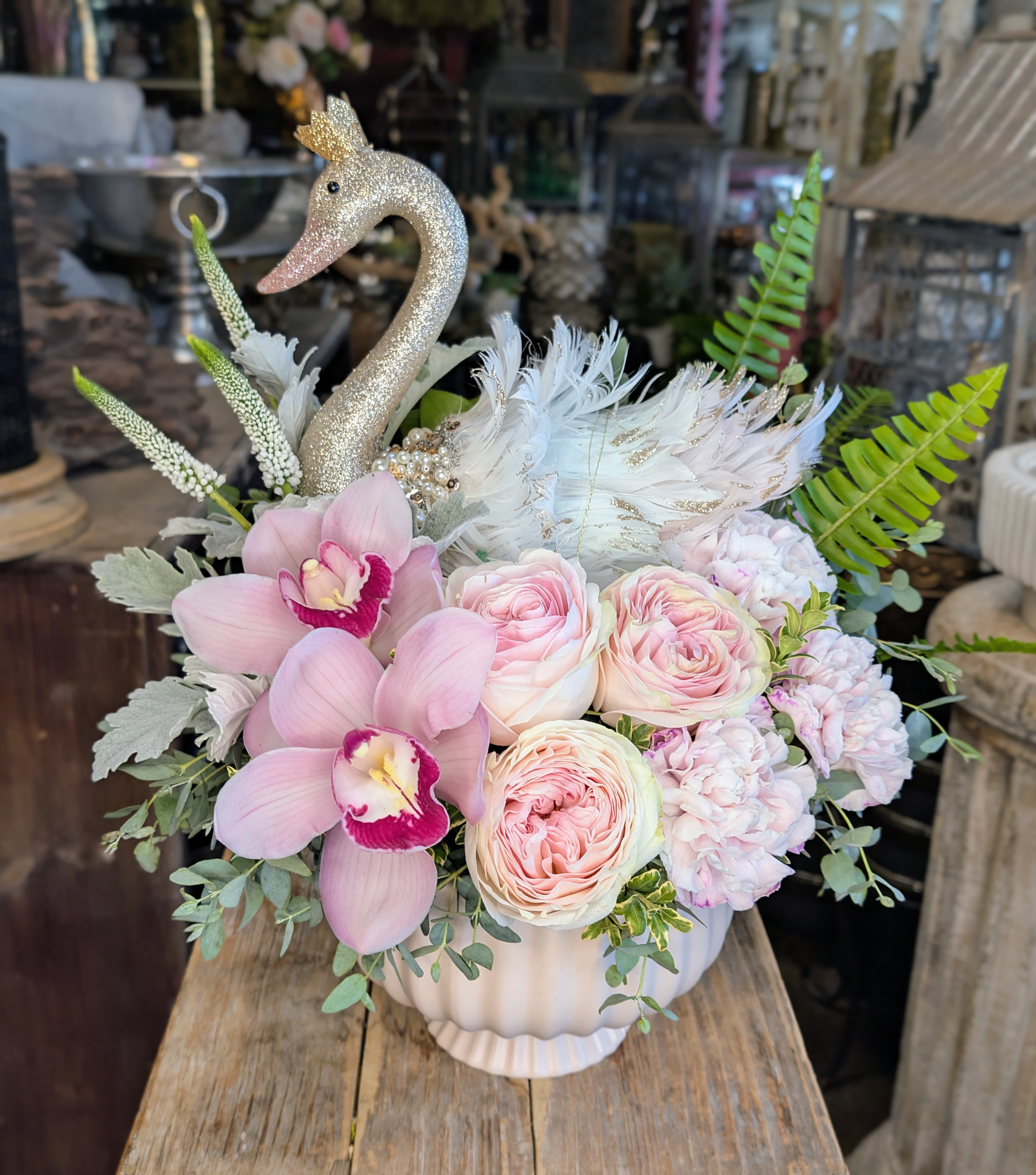 Pink floral arrangement in a white vase with a glitter swan topper