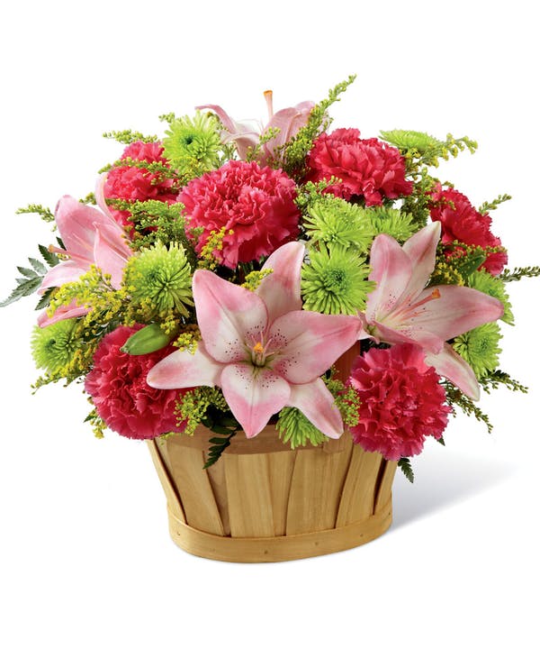 Pink lilies and carnations in a wooden basket
