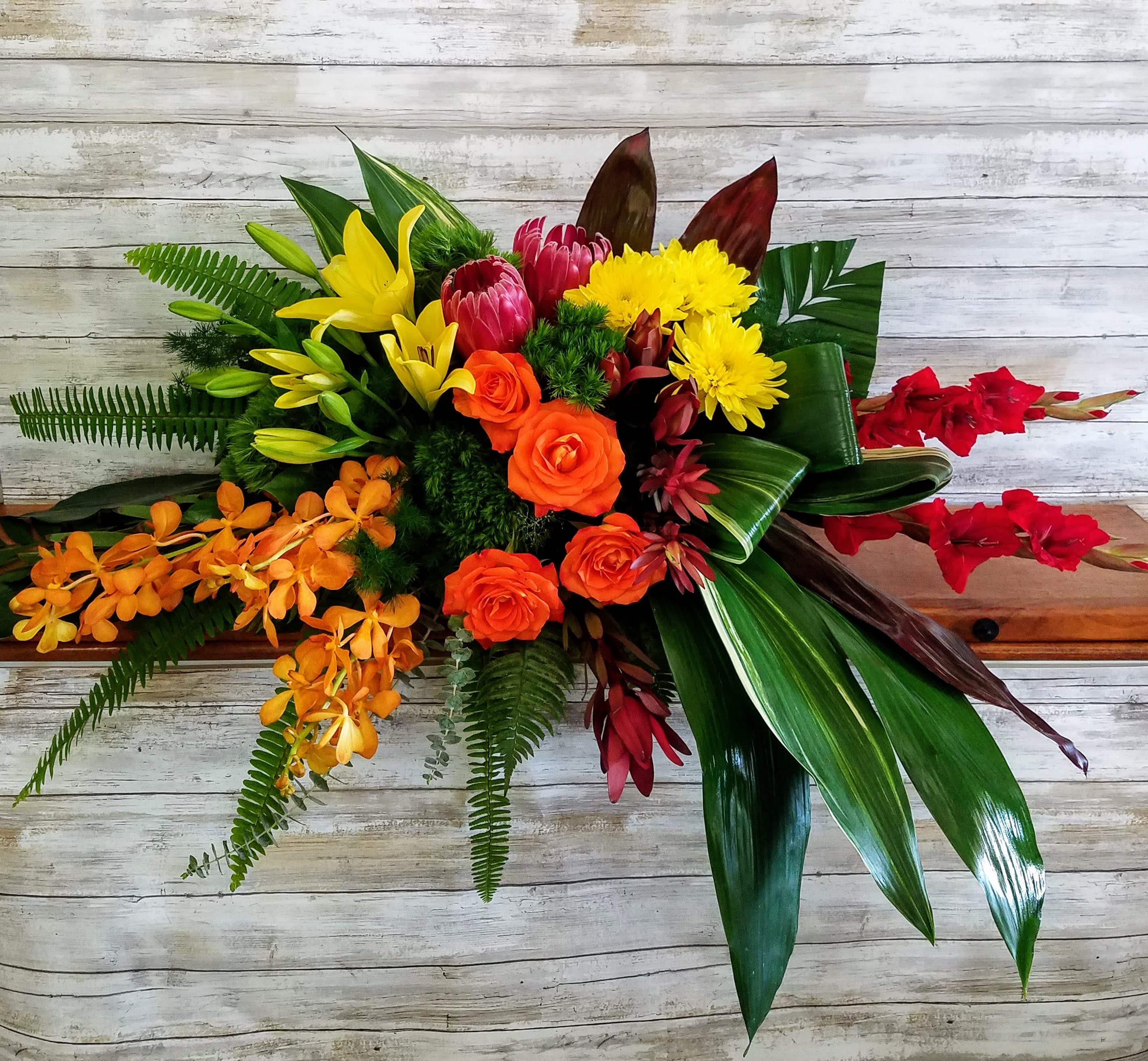 Tropical bouquet with orange roses, yellow lilies, and red orchids