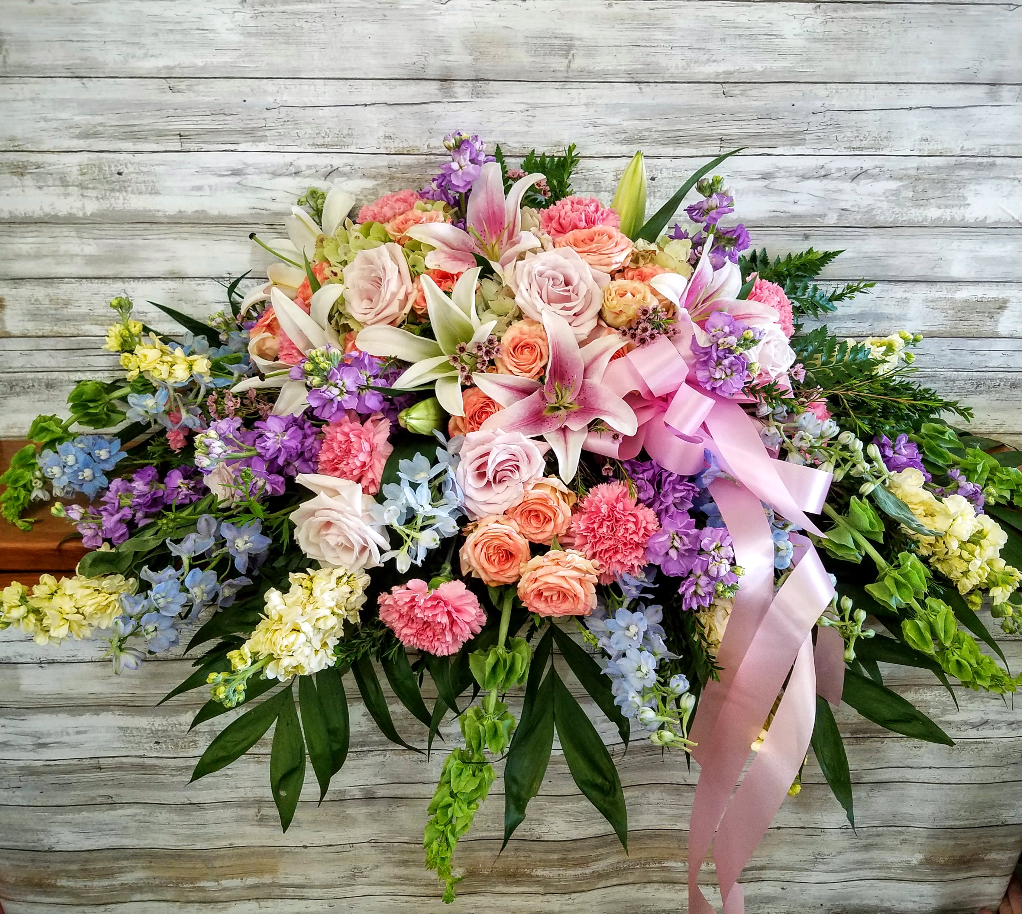 Large pastel floral spray with lilies, roses, and ribbon