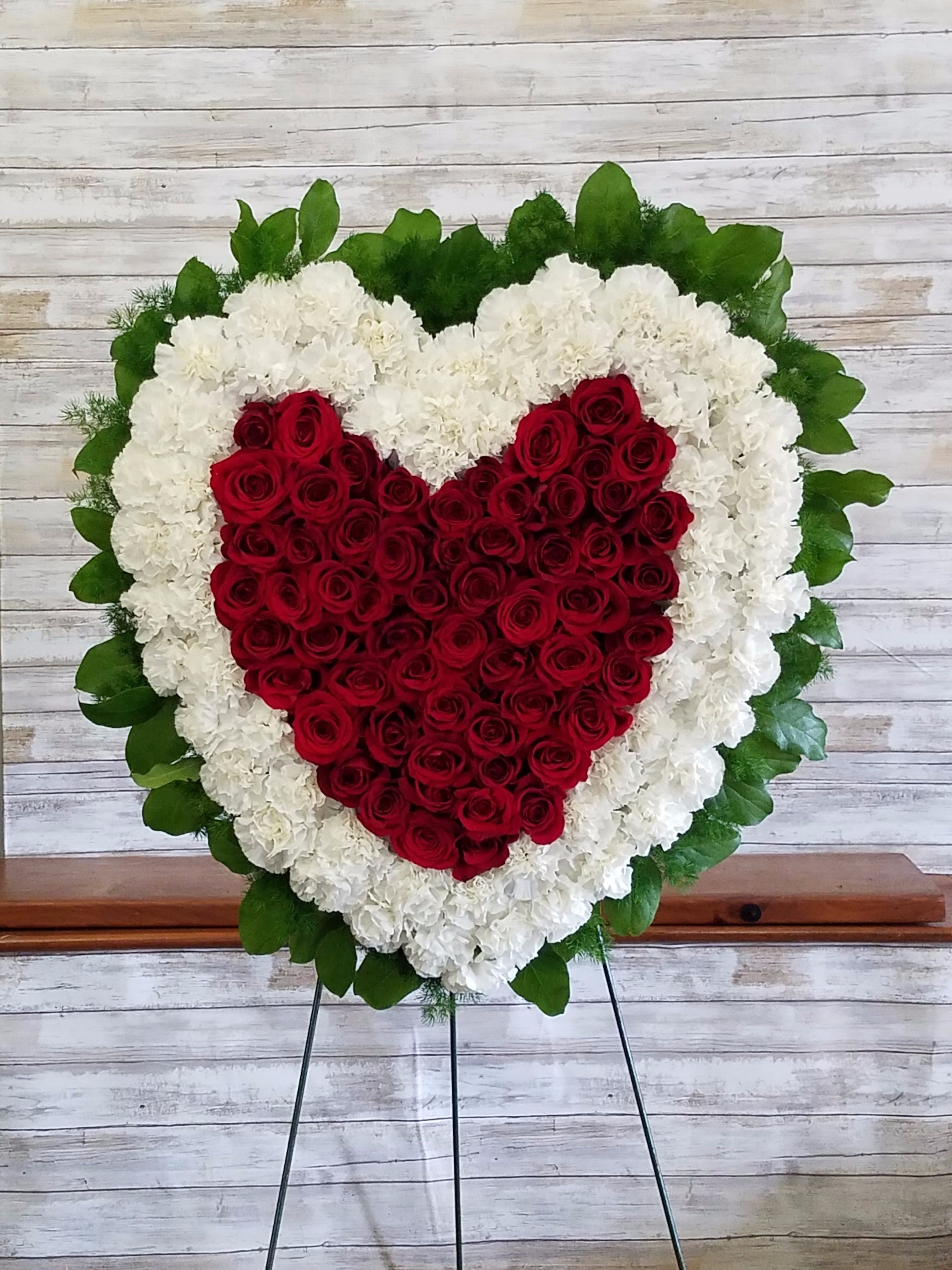 Love &amp; Peace Heart Tribute - Make a strong, stylish statement of love with this beautiful heart-shaped wreath. Presented on a funeral easel, the rich red rose sympathy arrangement is a lovely standing spray to place on the altar or by the entrance to the service.  Measures 28" 