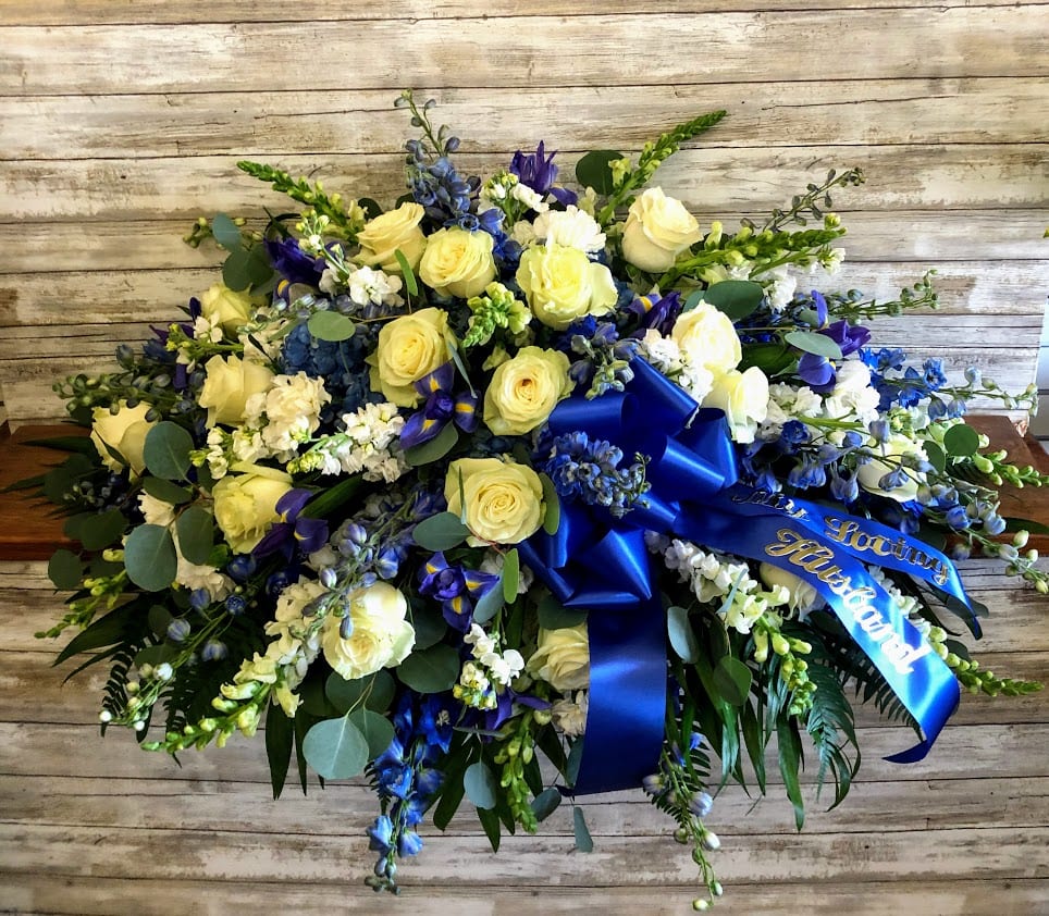 Blue and yellow floral spray with ribbon on a wooden background