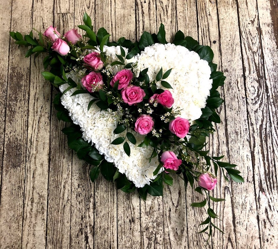Heart-shaped floral arrangement with pink roses and white flowers