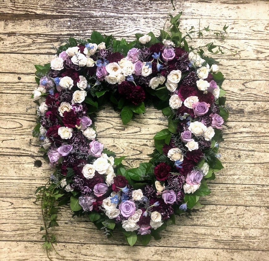 Heart-shaped floral wreath with purple, white, and burgundy roses