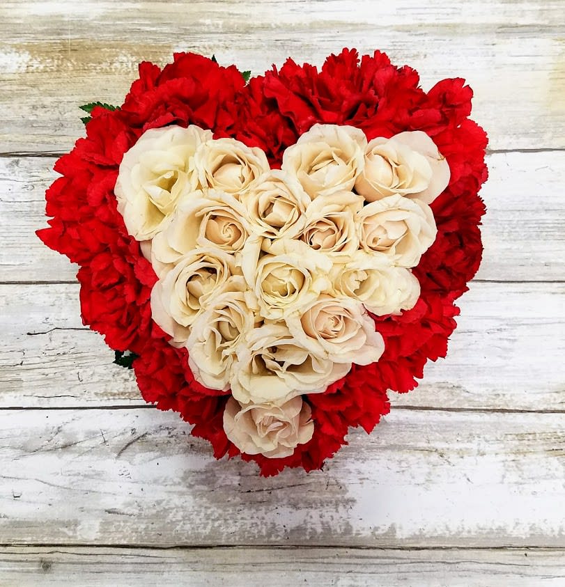 Heart-shaped bouquet of cream roses surrounded by red carnations
