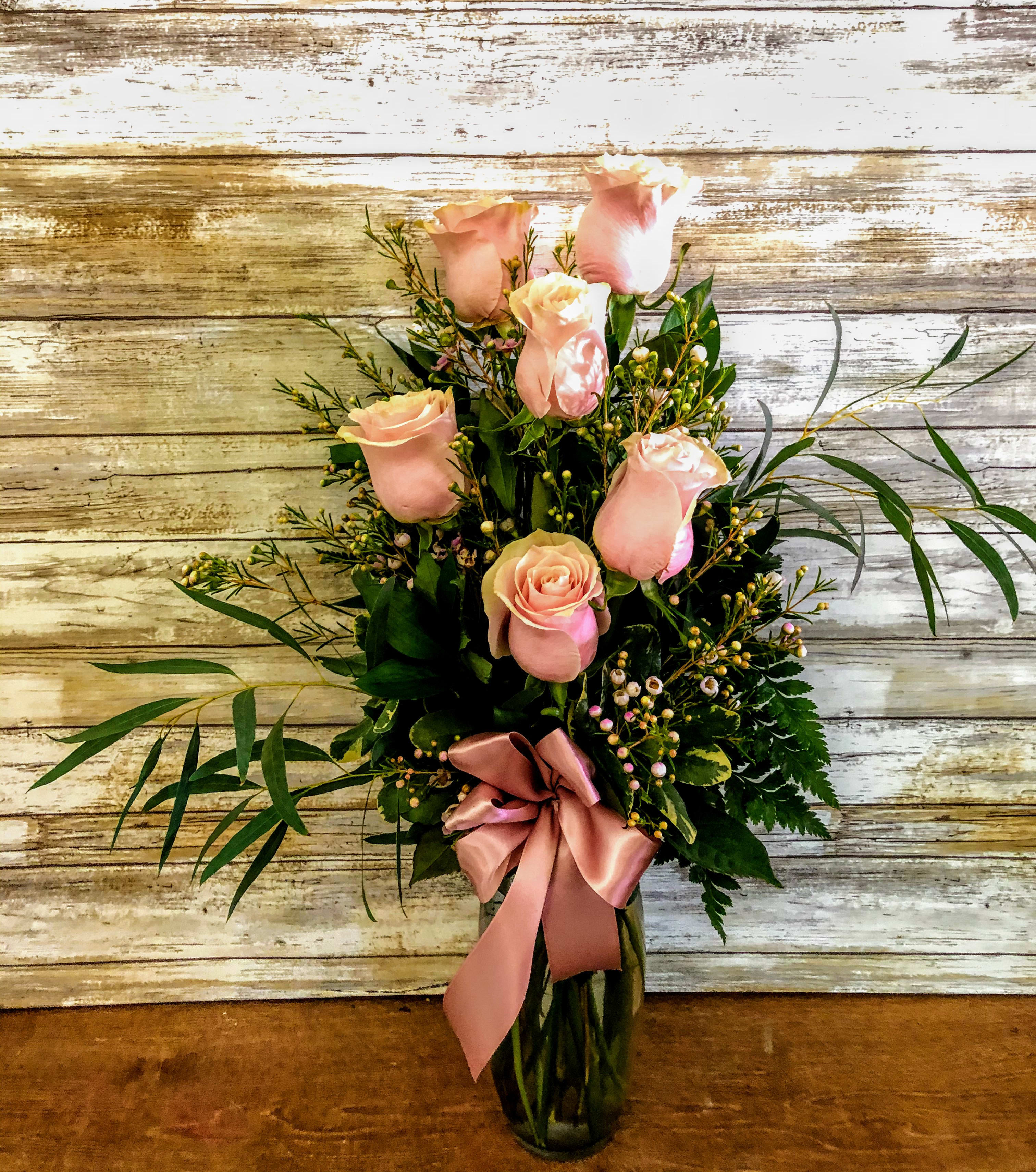 Pink roses arranged in a glass vase with a satin ribbon