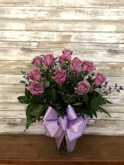 Pink roses in a glass vase with a lavender ribbon