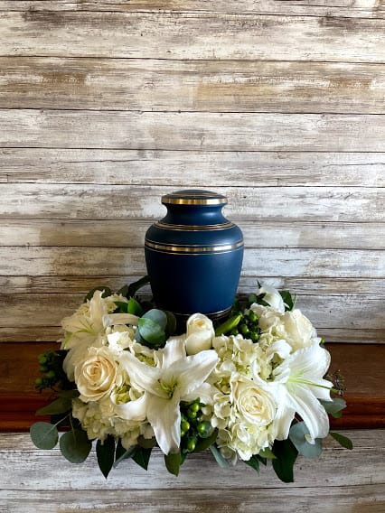 White floral urn arrangement with lilies and roses around a blue urn