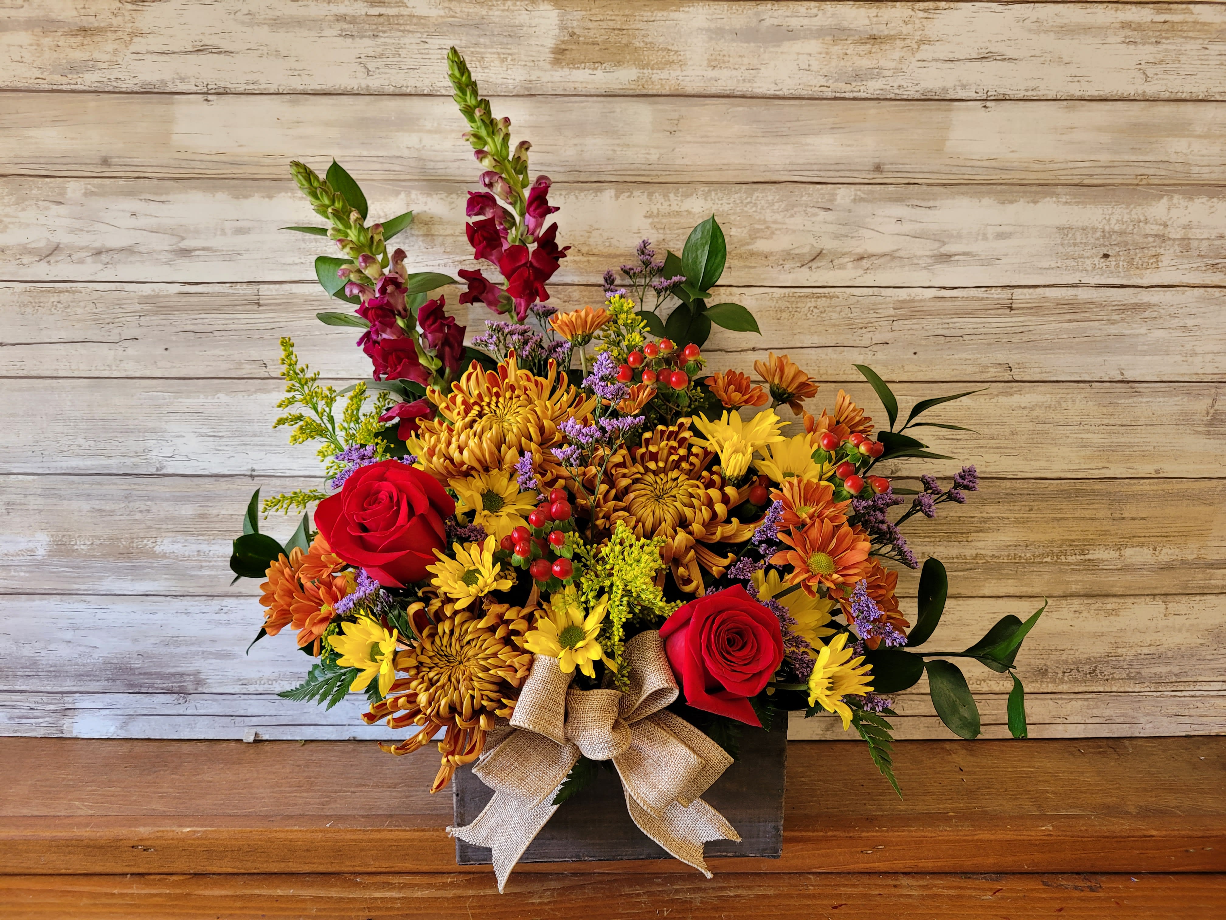 Fall Styled Wooden Box- Substitutions Will be Necessary - Send a burst of Fall with this beautiful wildflower box. Filled with seasonal flowers in mixed colors. The photo is a sample and the actual item delivered will be different colors and flowers depending on local stock.   One-Sided orientation  