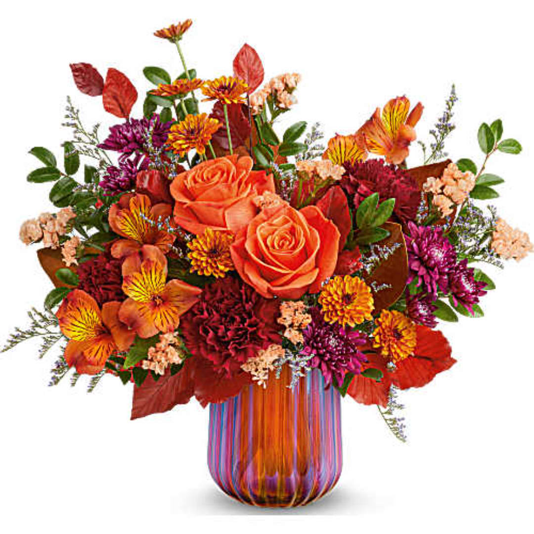 Orange and red mixed bouquet in a striped glass vase
