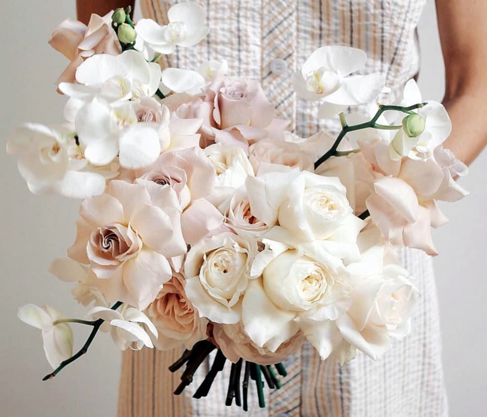 Bouquet of pale roses and white orchids held in hand