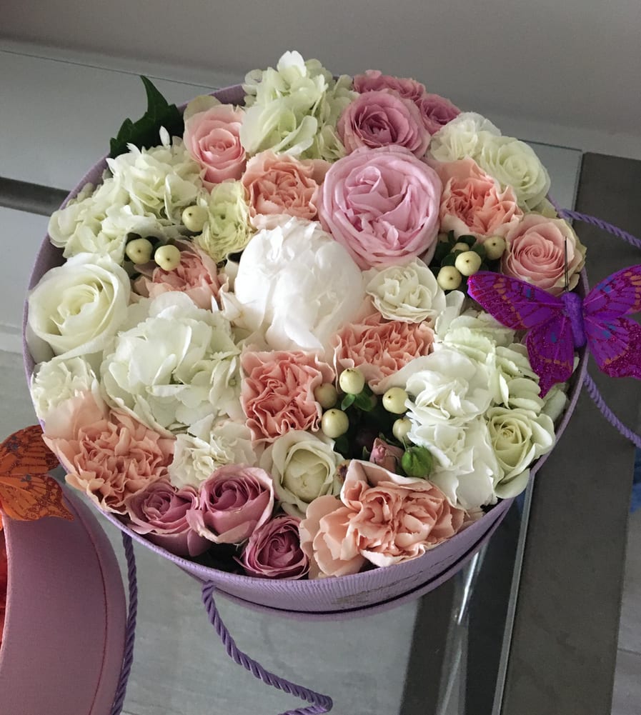 Round box of pink and white roses with carnations and a purple butterfly decoration