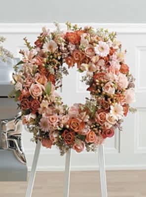 Large floral wreath of peach and blush roses on a stand