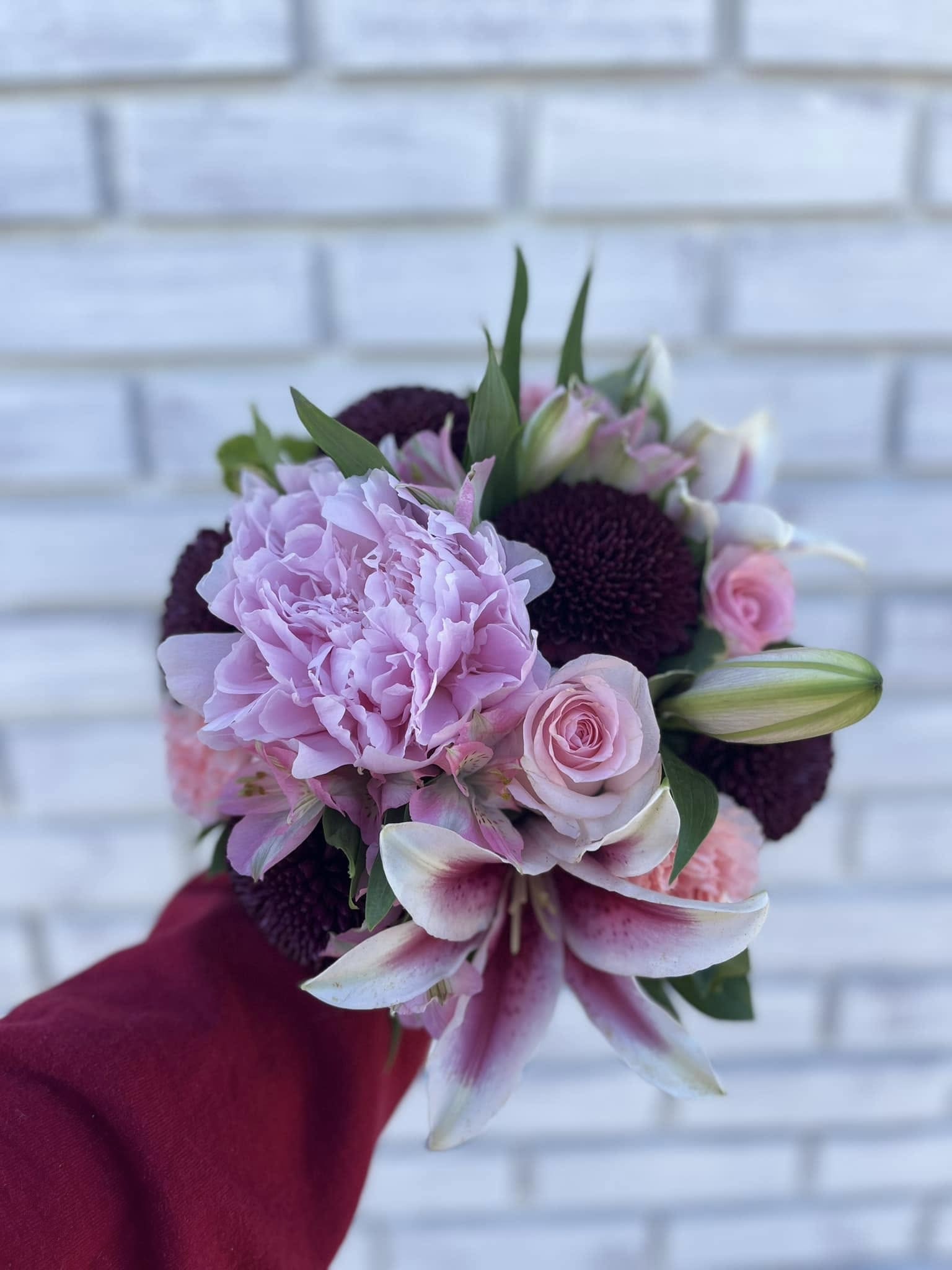 Handheld bouquet of pink and white flowers with dark purple blooms