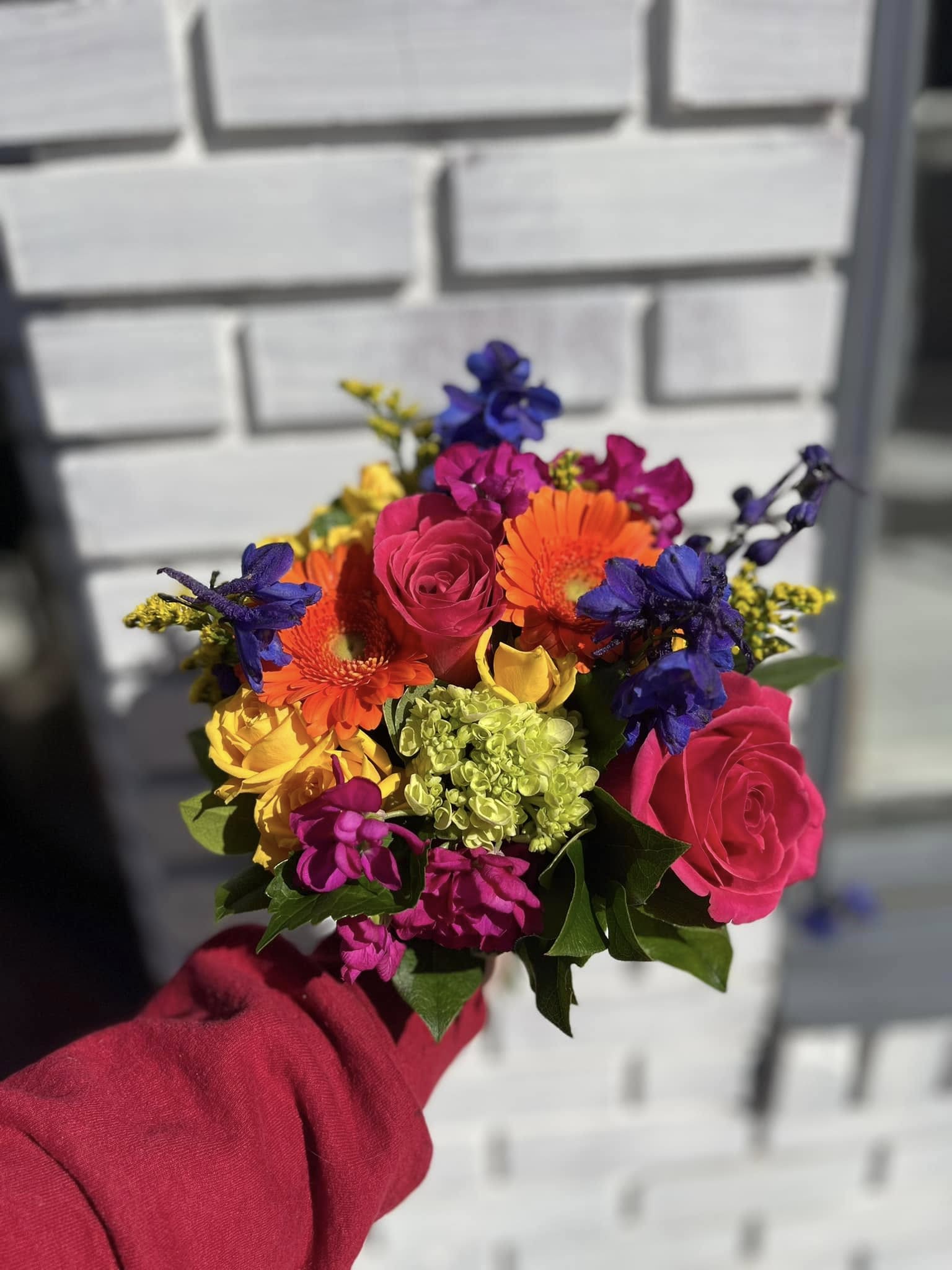 Handheld bouquet of bright mixed flowers with roses and gerberas
