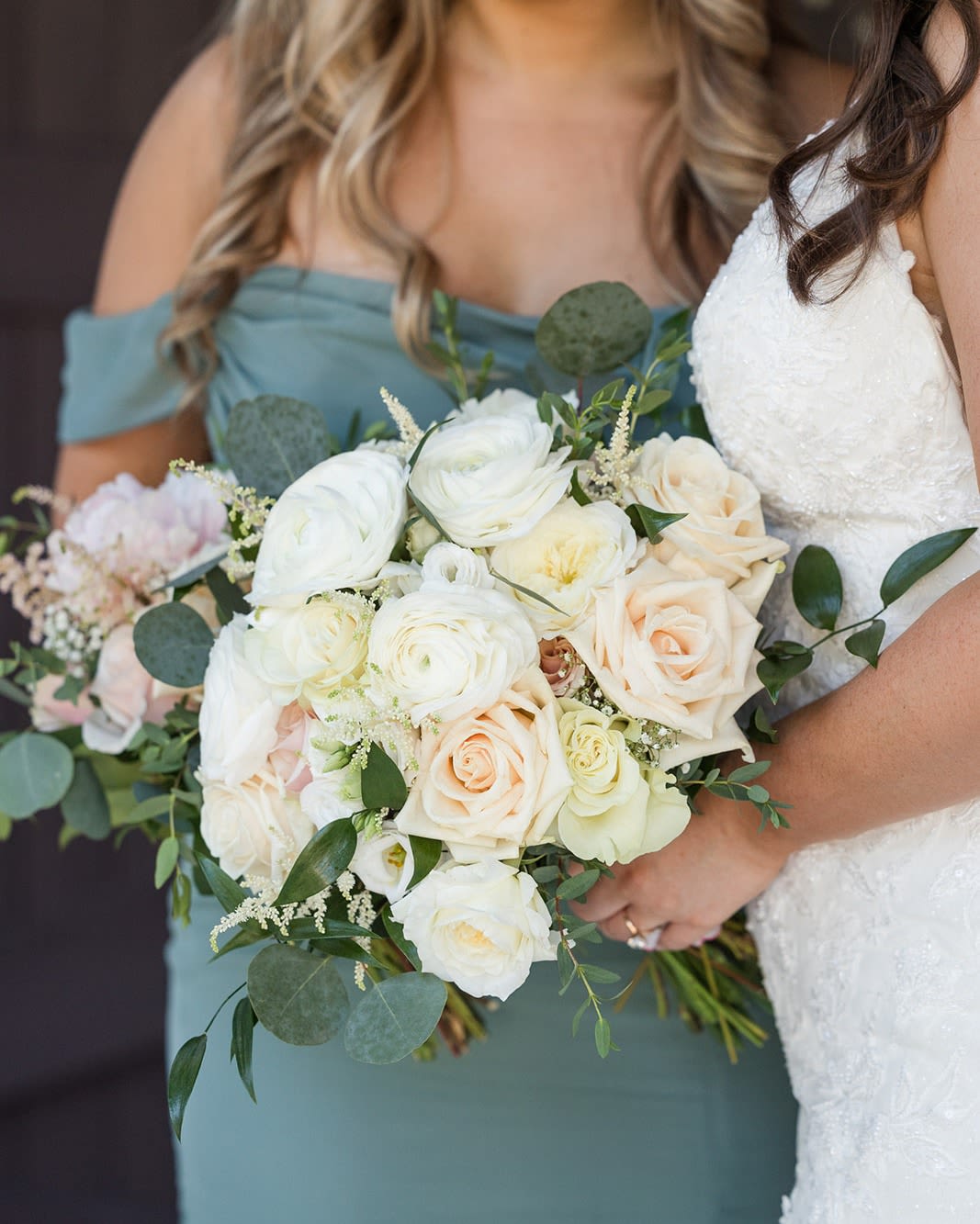 Bride and bridesmaid holding white and blush rose bouquets
