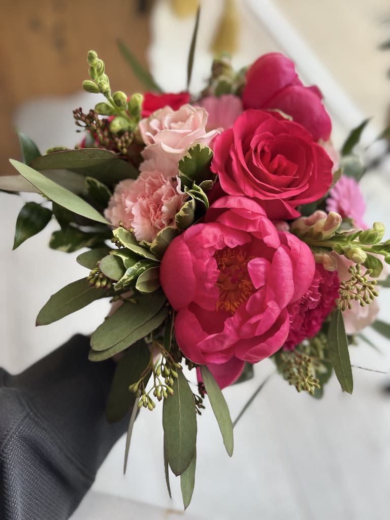 Handheld bouquet of hot pink peonies and pale pink roses