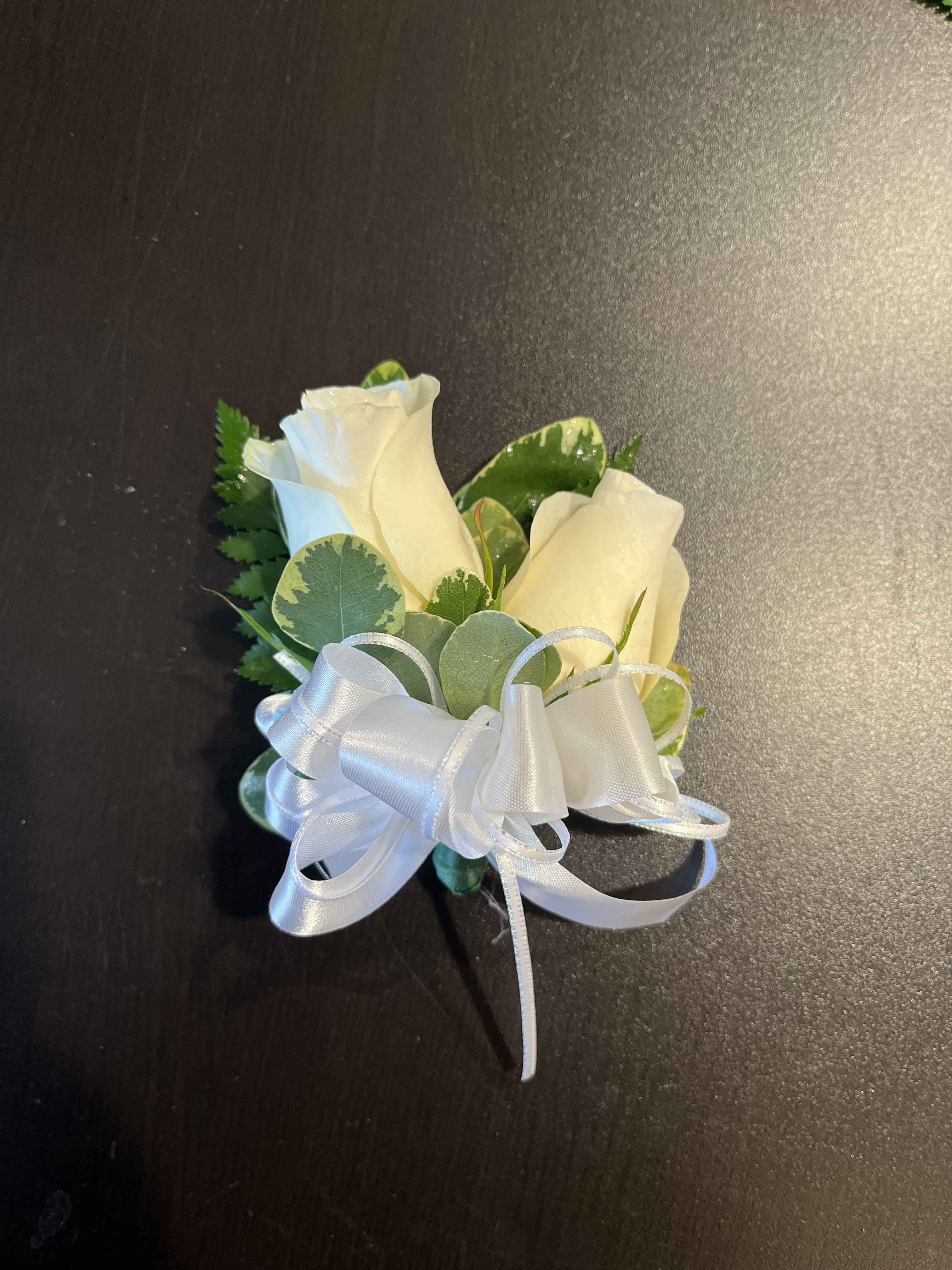 Two white rose blooms with a white ribbon bow