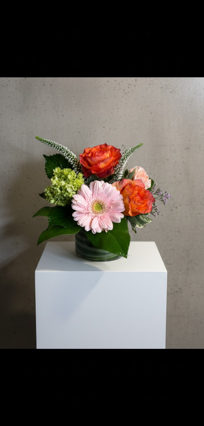 Small bouquet of orange roses and a pink gerbera daisy in a glass vase