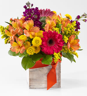Bright mixed bouquet in a wooden box with an orange ribbon