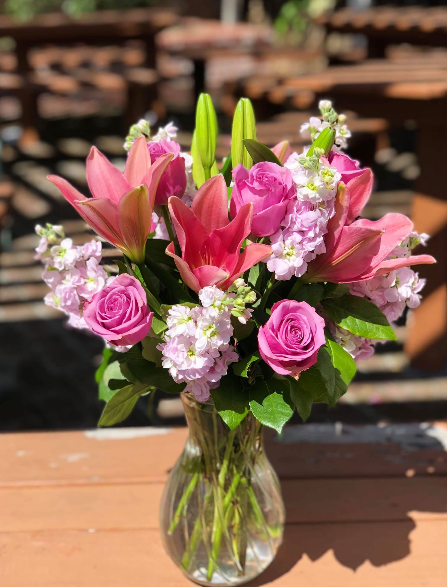 Pink roses and lilies arranged in a clear glass vase