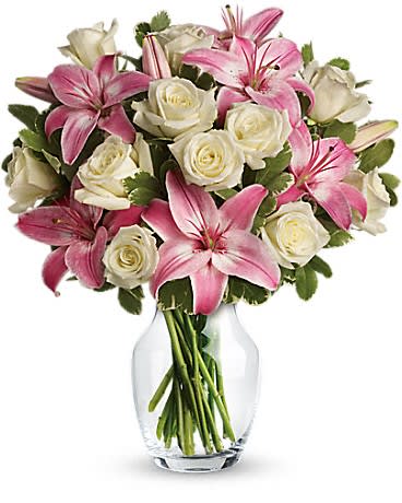 Pink lilies and white roses arranged in a clear glass vase
