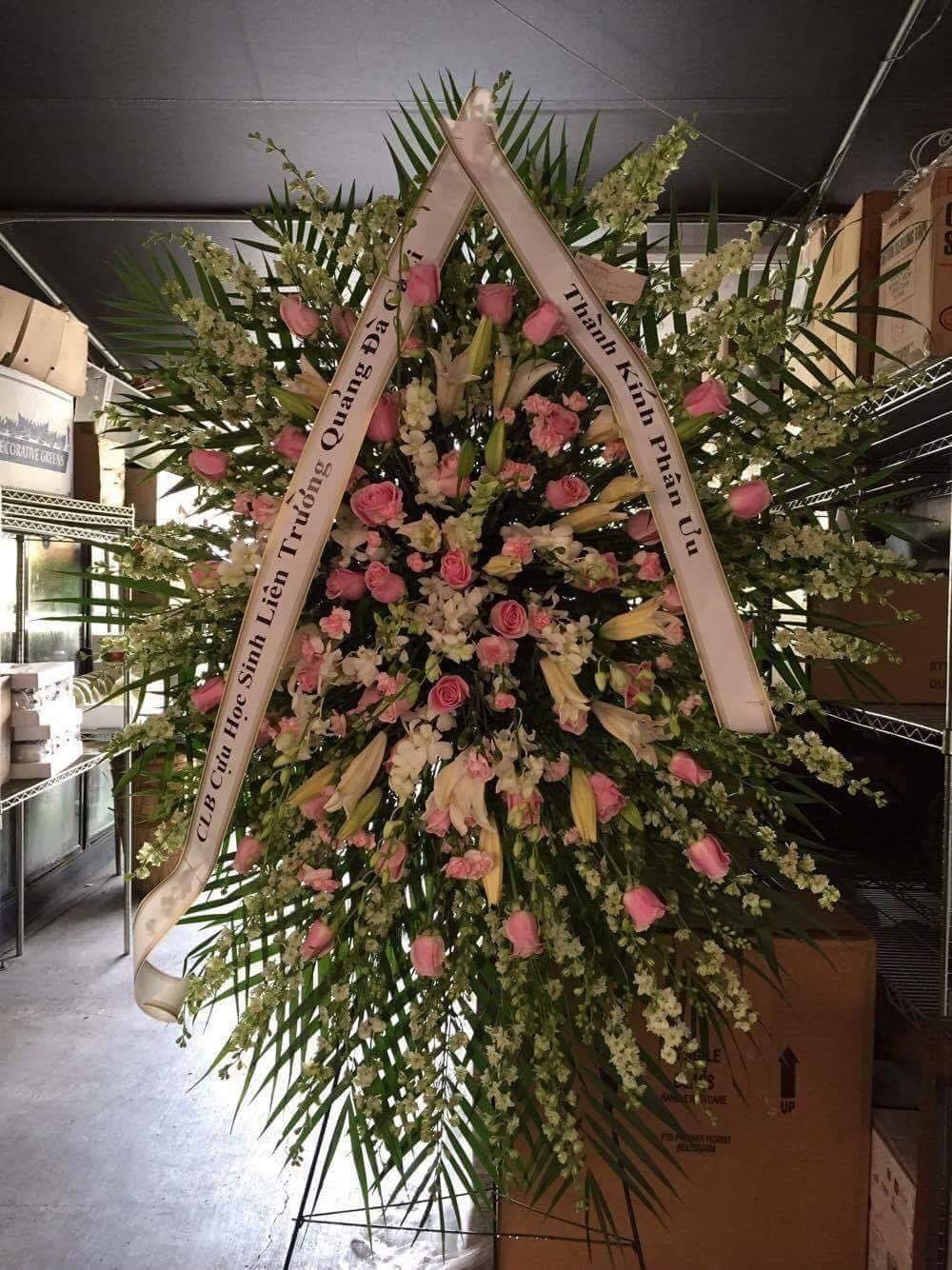 Large standing floral wreath with pink roses and white lilies on a ribboned frame