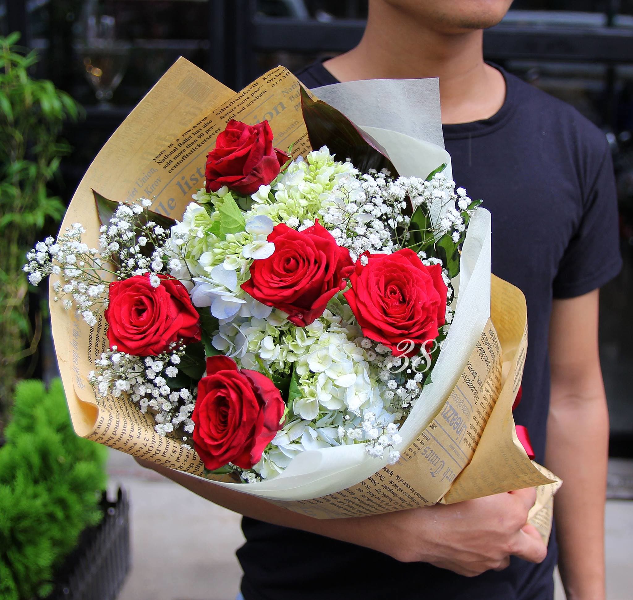 Bouquet of red roses and white hydrangeas wrapped in paper